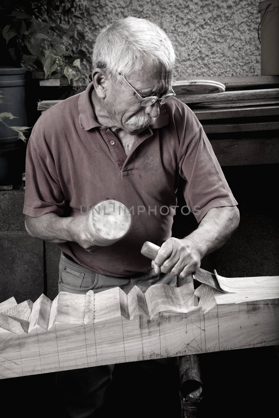 Old woodcarver working with mallet and chiesel, vintage style