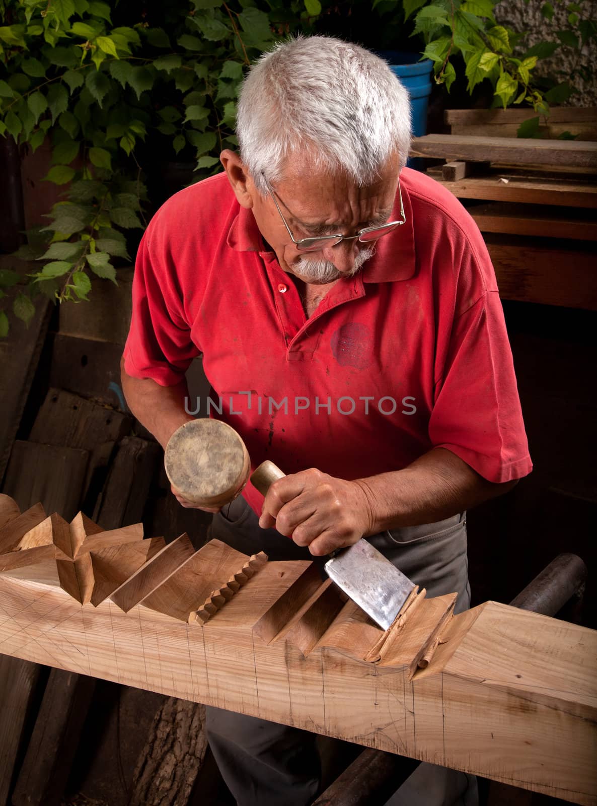 Old woodcarver working with mallet and chiesel