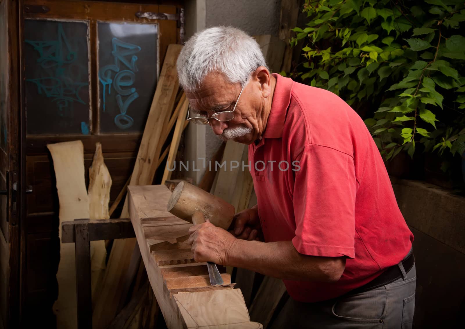 Old woodcarver working with mallet and chiesel