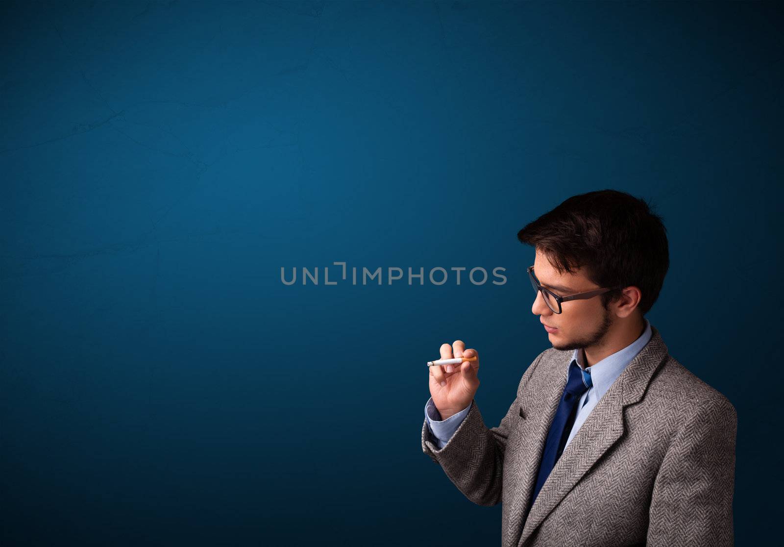 Handsome young man smoking cigarette with copy space