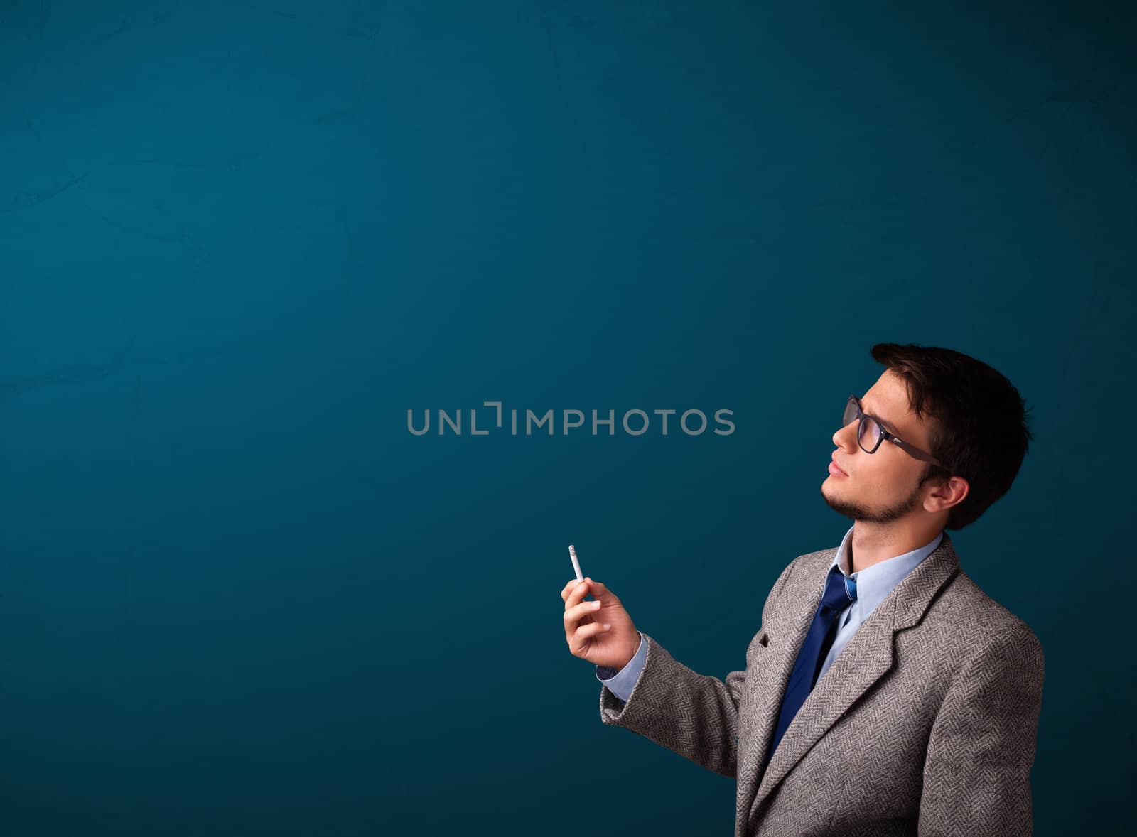 Young man smoking cigarette with copy space by ra2studio