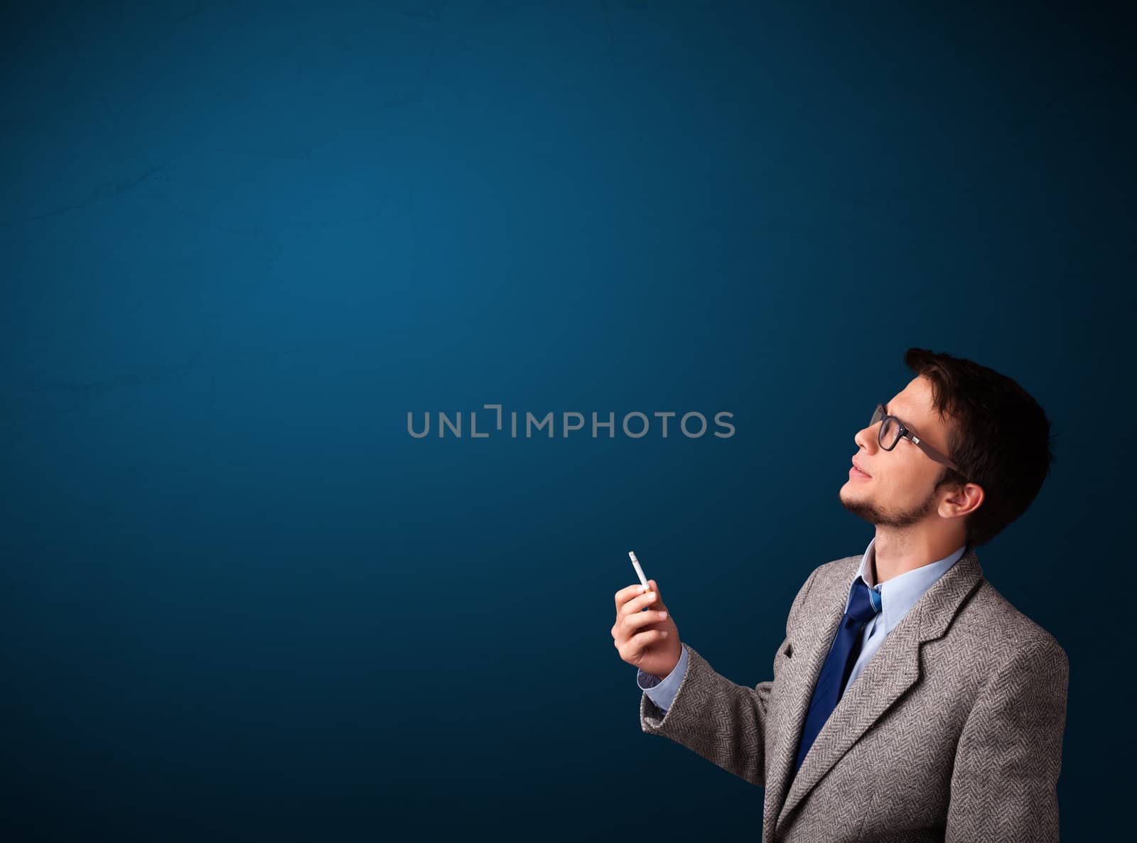 Handsome young man smoking cigarette with copy space
