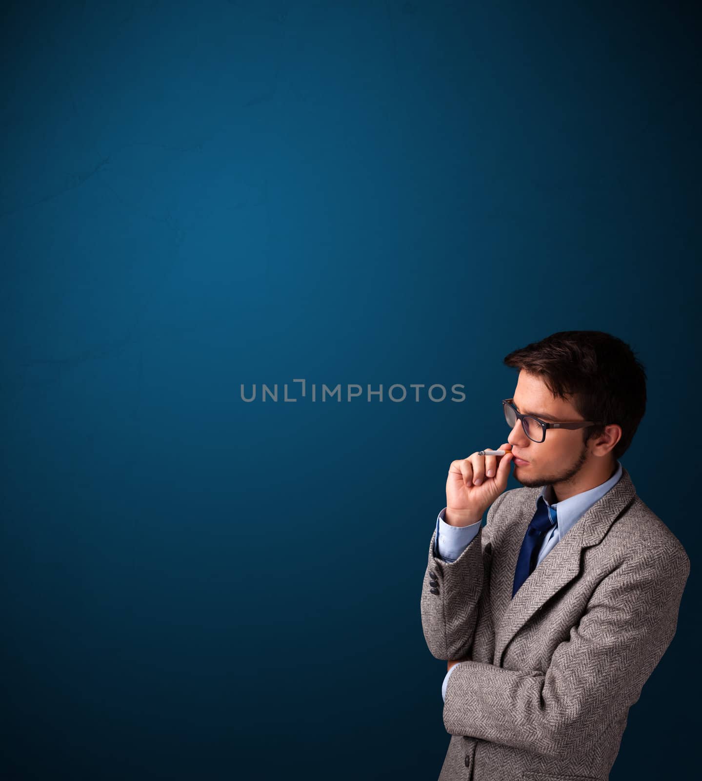 Handsome young man smoking cigarette with copy space