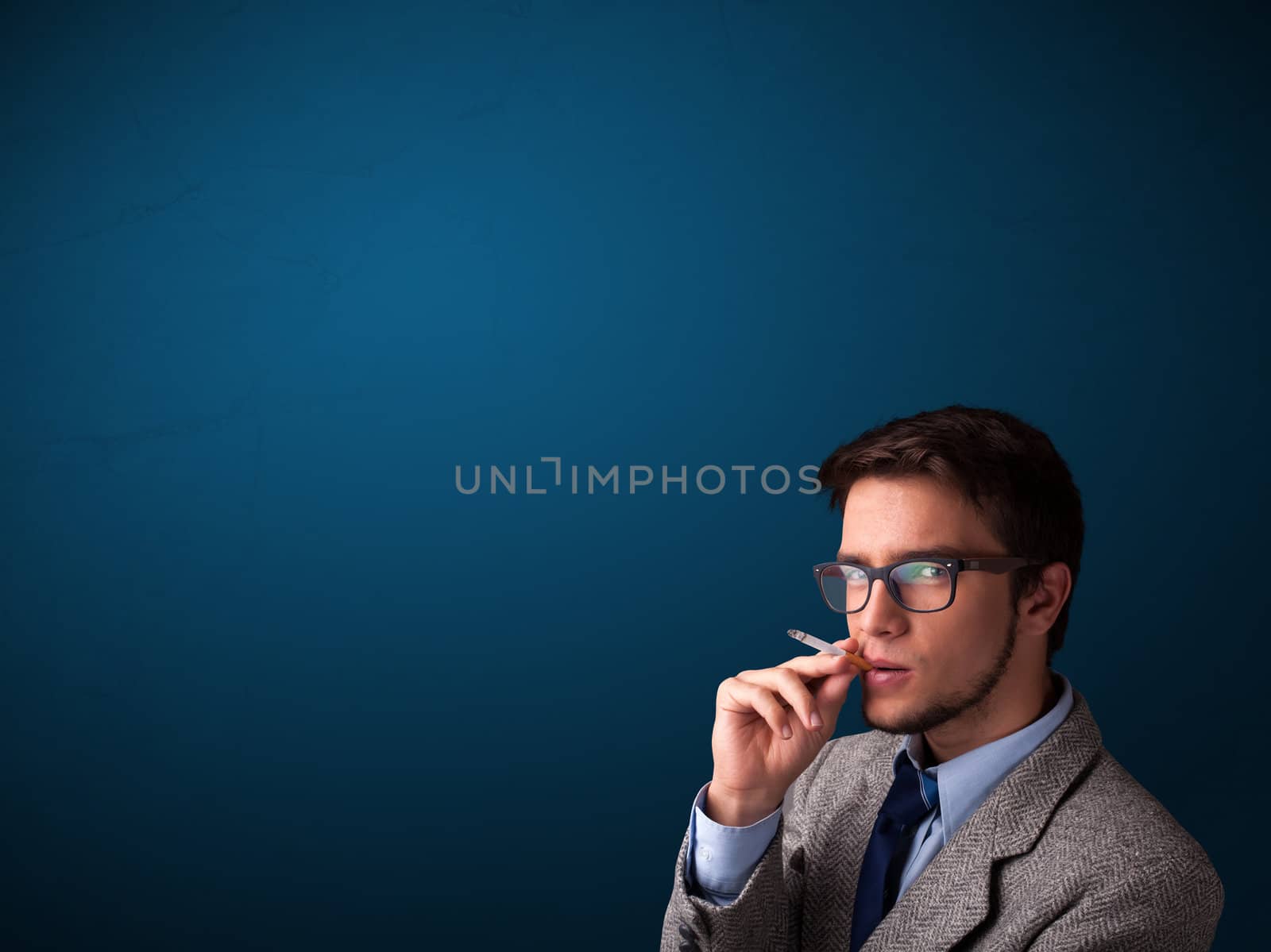 Handsome young man smoking cigarette with copy space