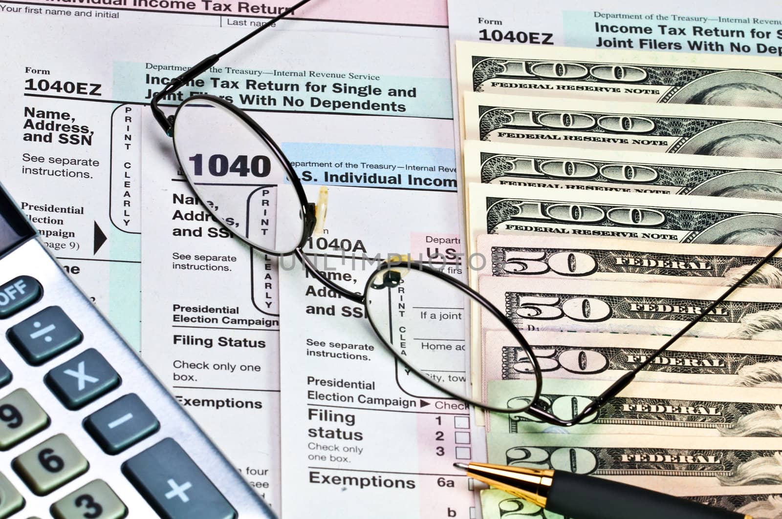 Tax forms 1040 with pen, glasses, calculator and money.