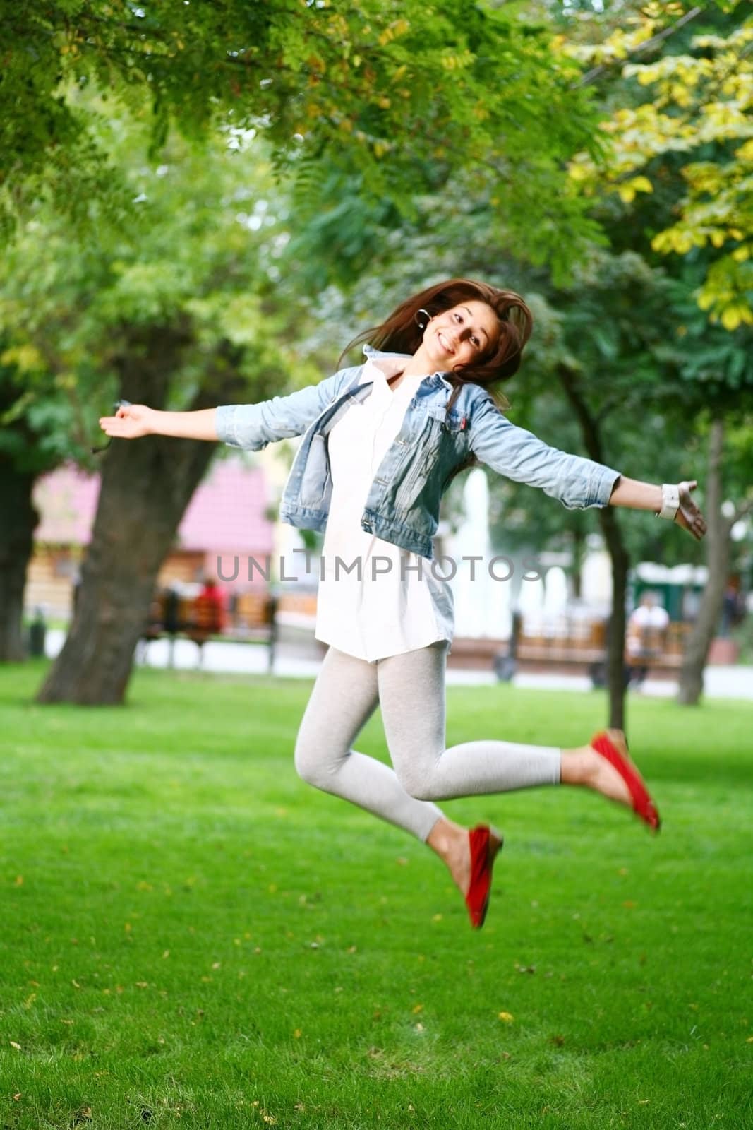 photo of young woman jamping on a grass