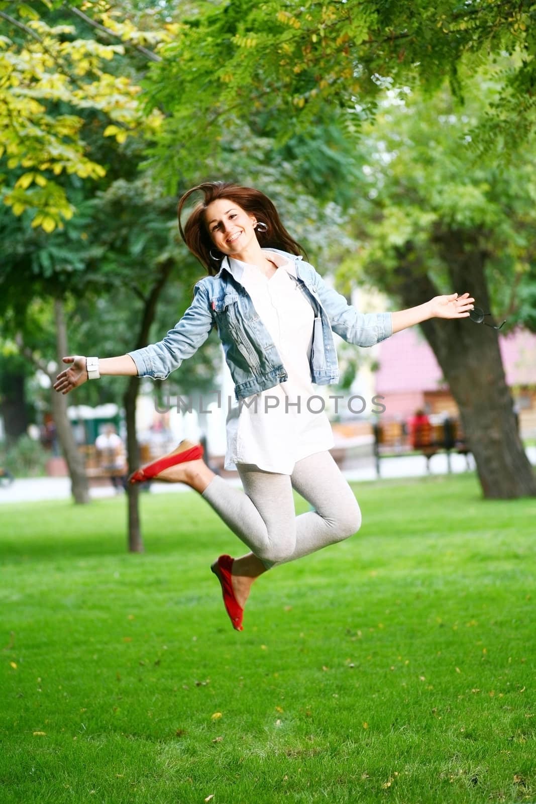 photo of young woman jamping on a grass