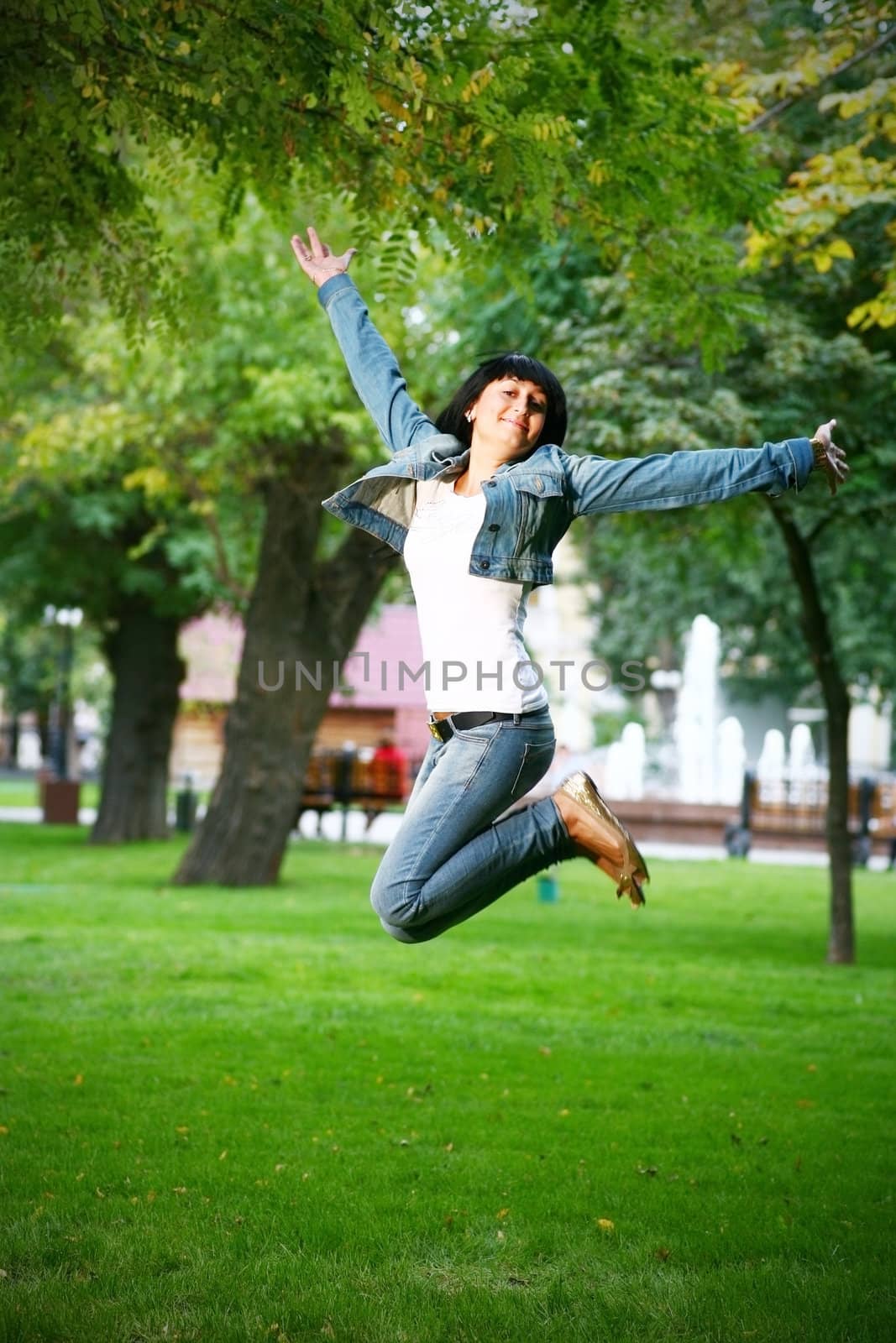 photo of young woman jamping on a grass