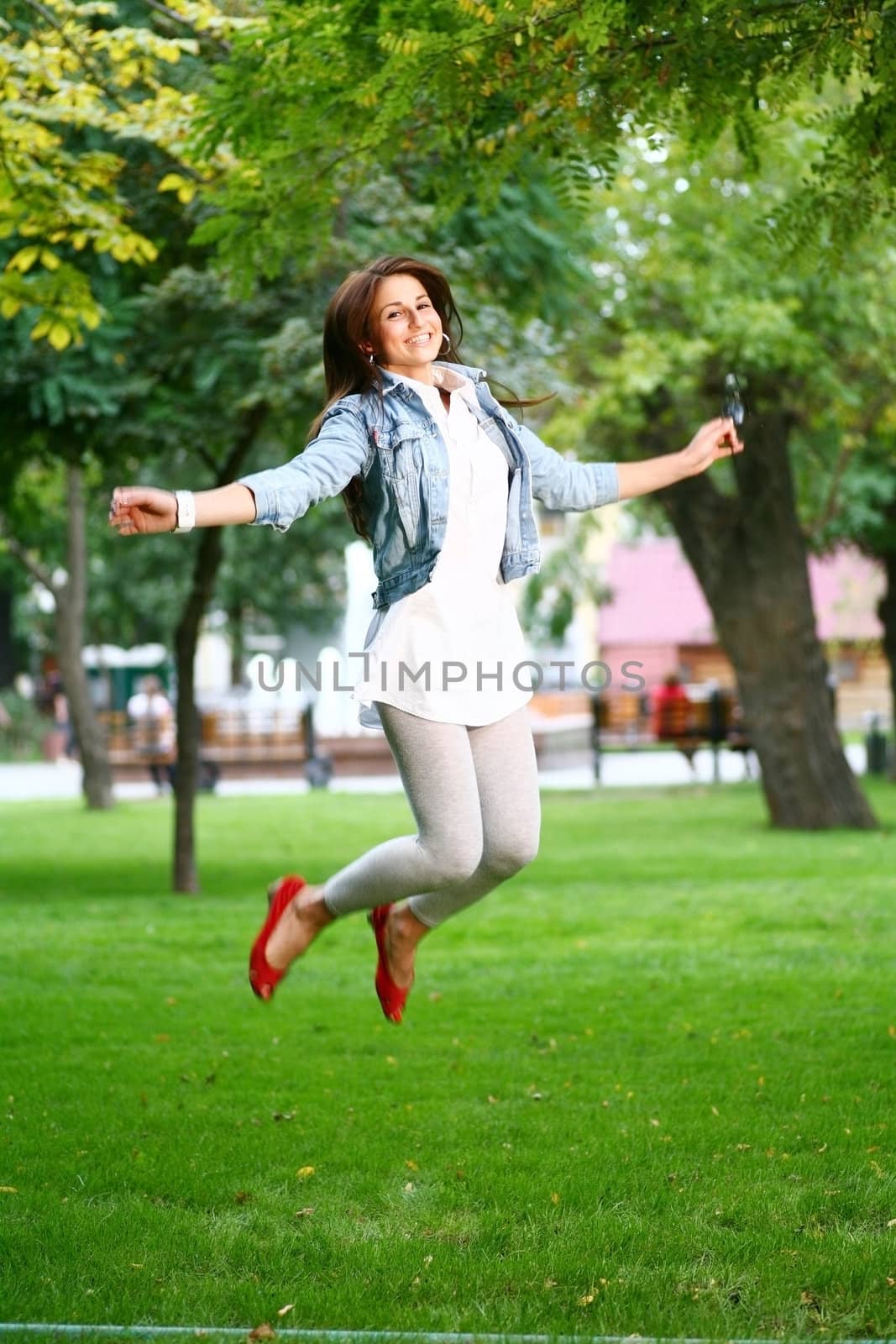 photo of young woman jamping on a grass