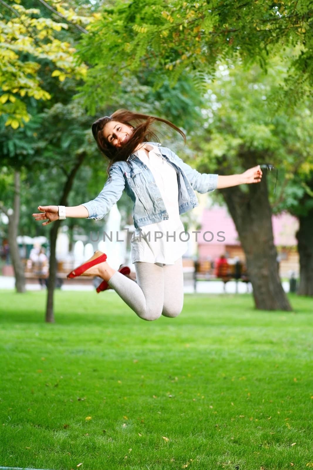 photo of young woman jamping on a grass