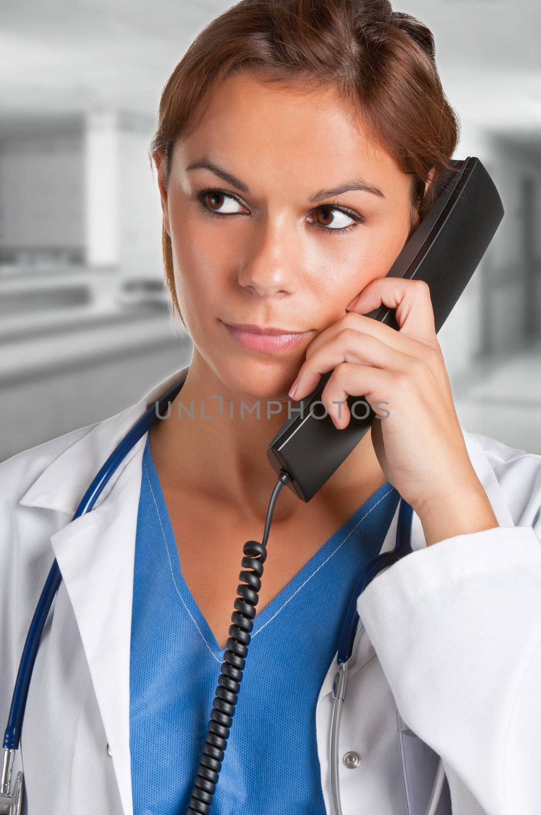 Young female doctor with scrubs and a stethoscope talking on the phone