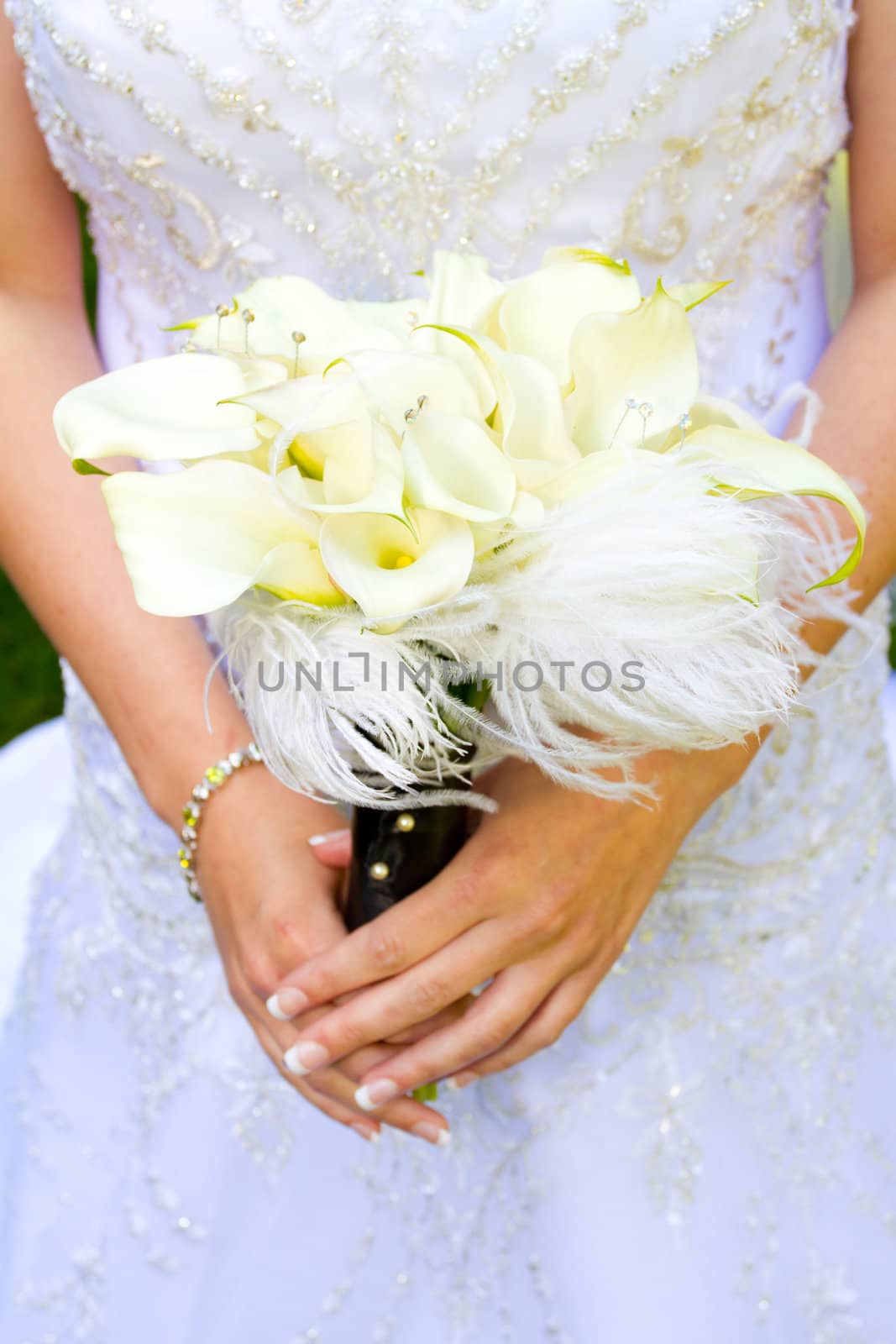 A beautiful bride in her white wedding dress holds her bouquet of flowers on her wedding day.