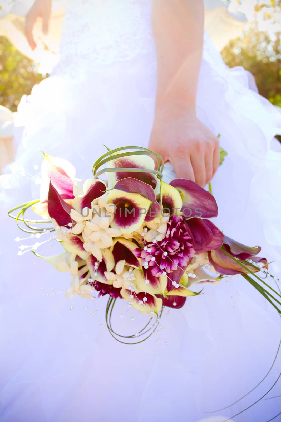 A beautiful bride in her white wedding dress holds her bouquet of flowers on her wedding day.