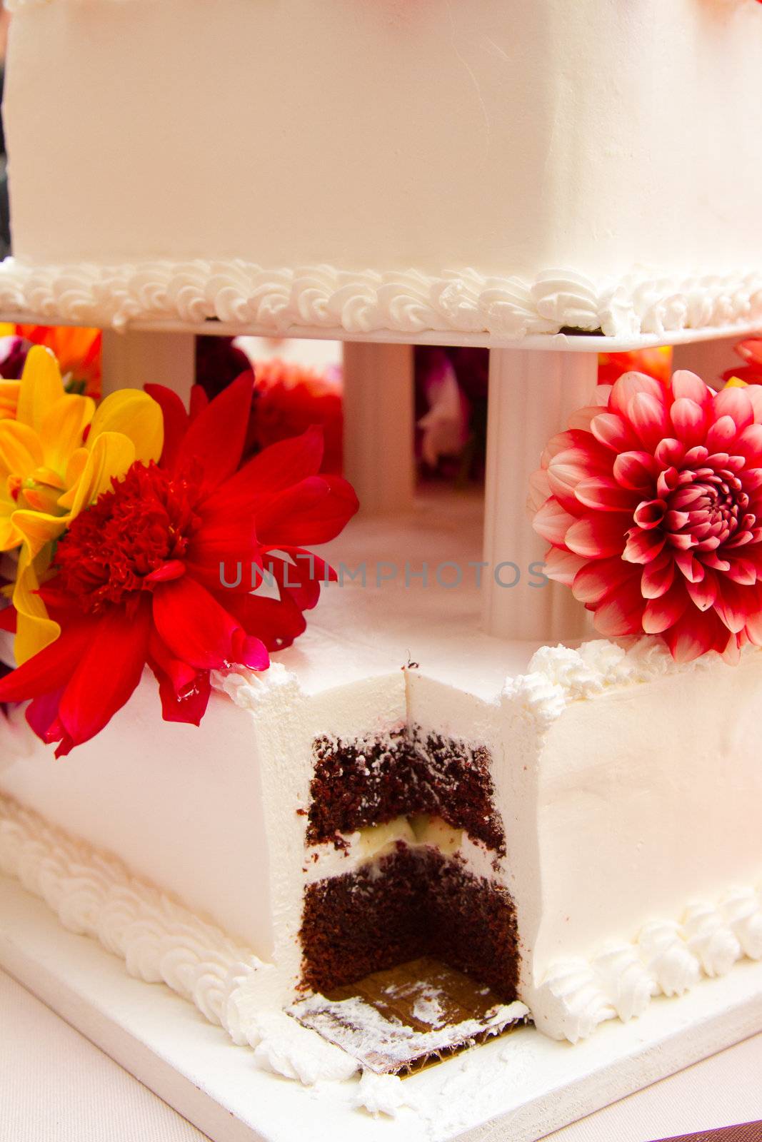 A cake with a big slice taken out by the bride and groom after they cut the cake.