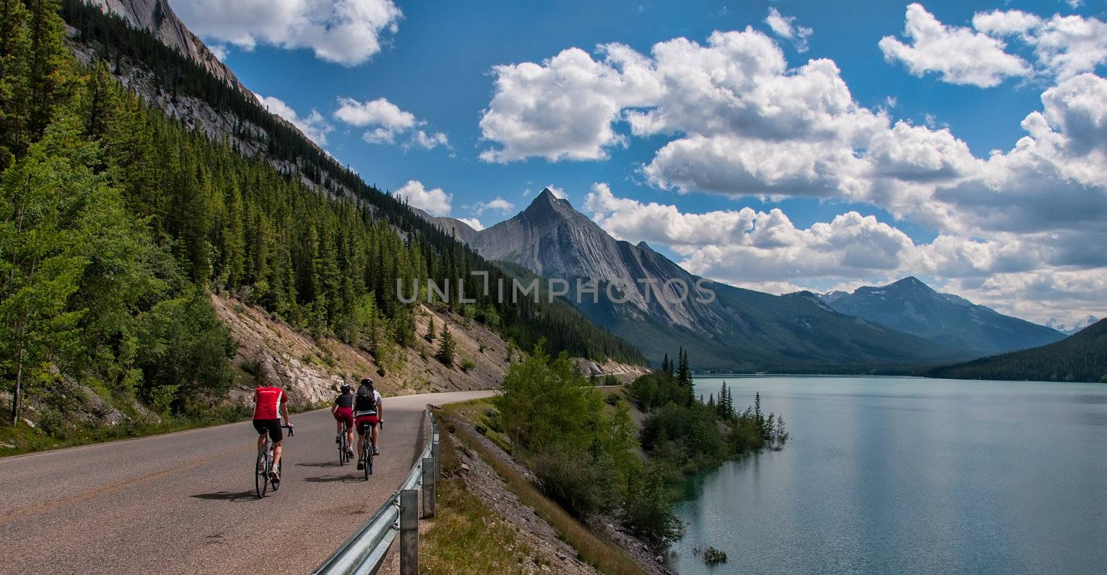 Three Cyclists On Road With Mountains by JamesWheeler