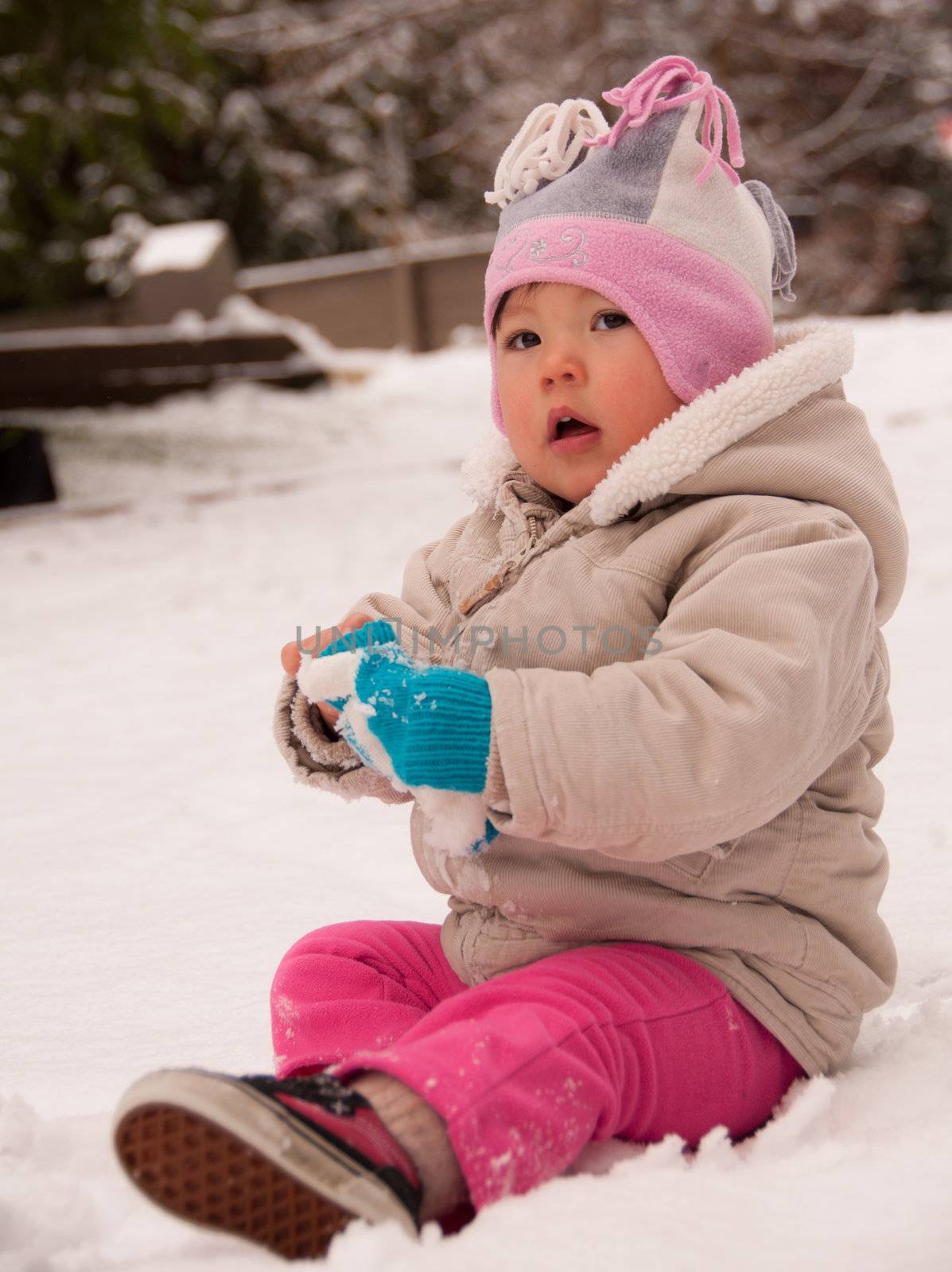Toddler sitting in snow looking cute
