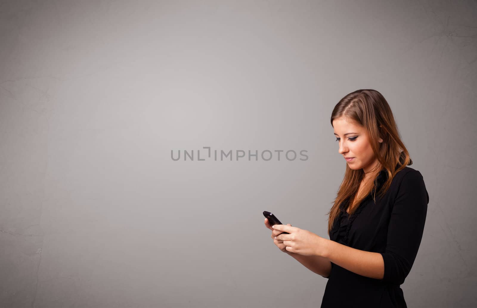young lady standing and holding a phone with copy space by ra2studio