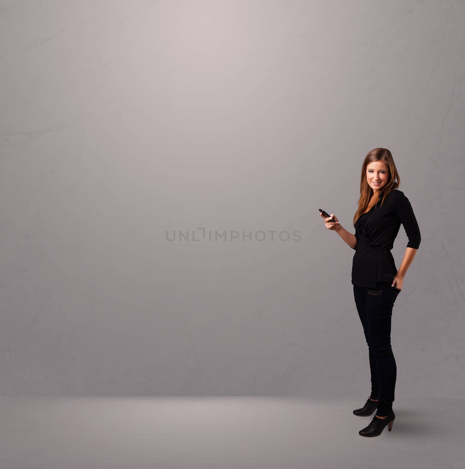 attractive young lady standing and holding a phone with copy space