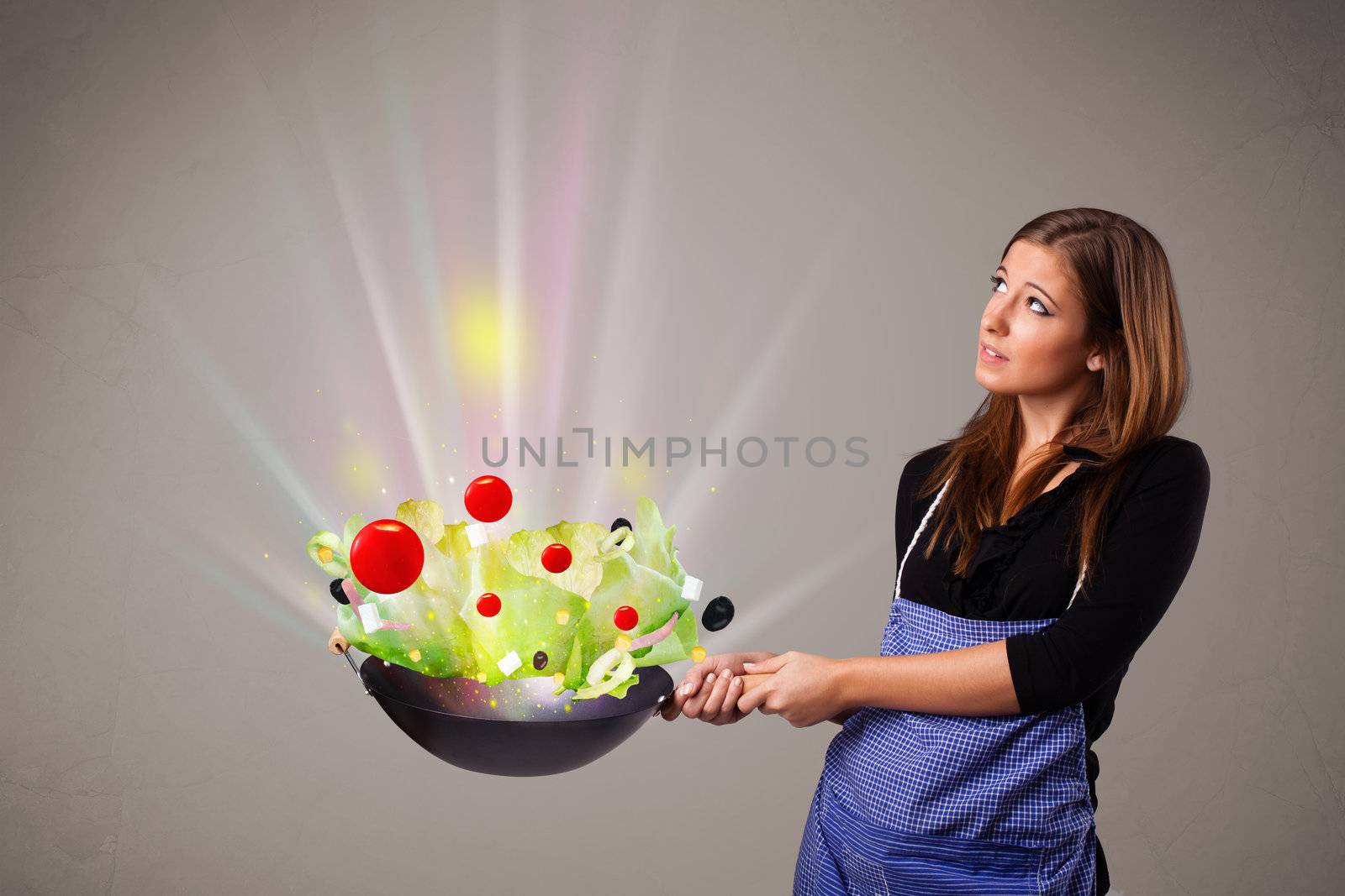 Beautiful young woman cooking fresh vegetables with abstract lights