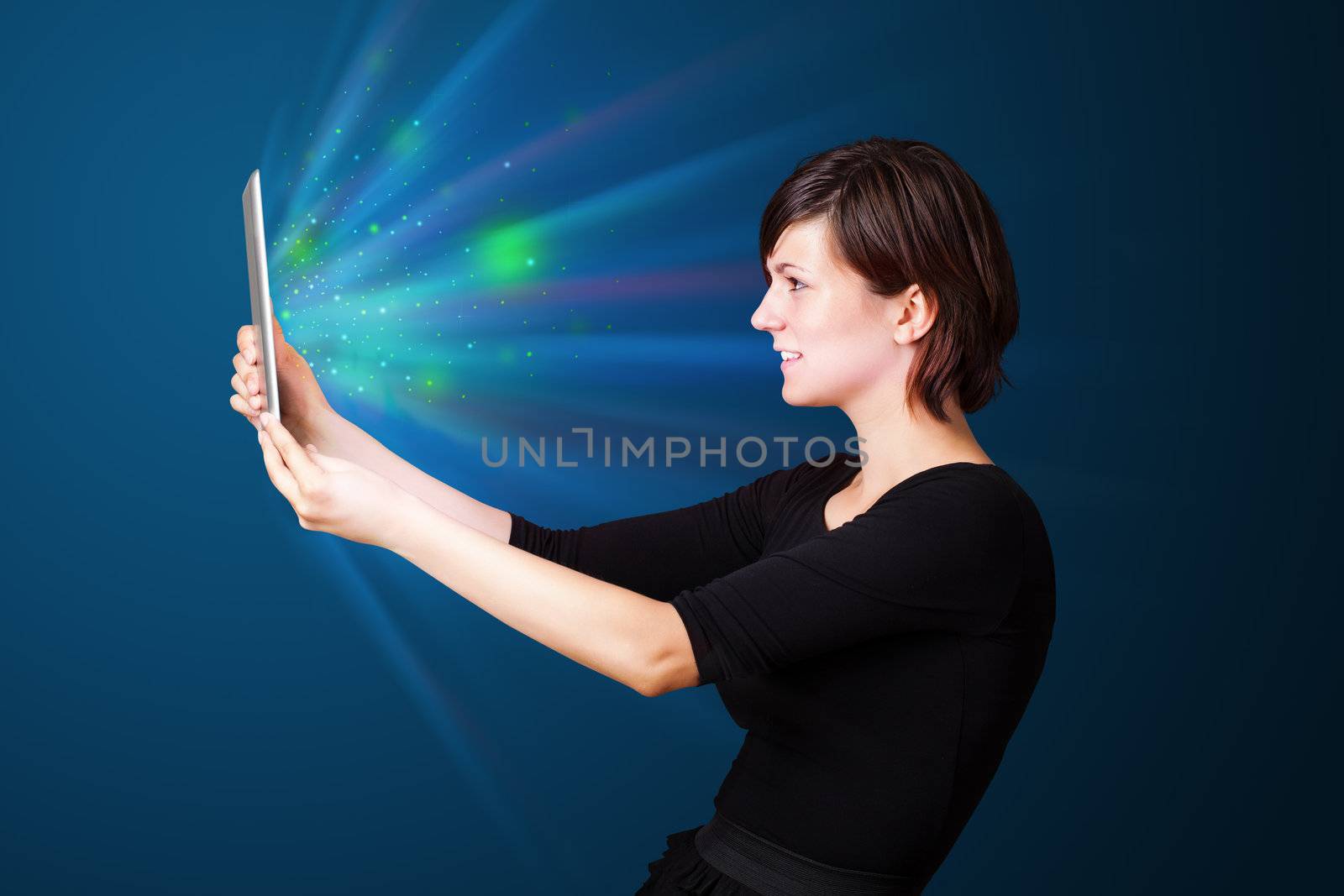 Young woman looking at modern tablet with abstract lights  by ra2studio