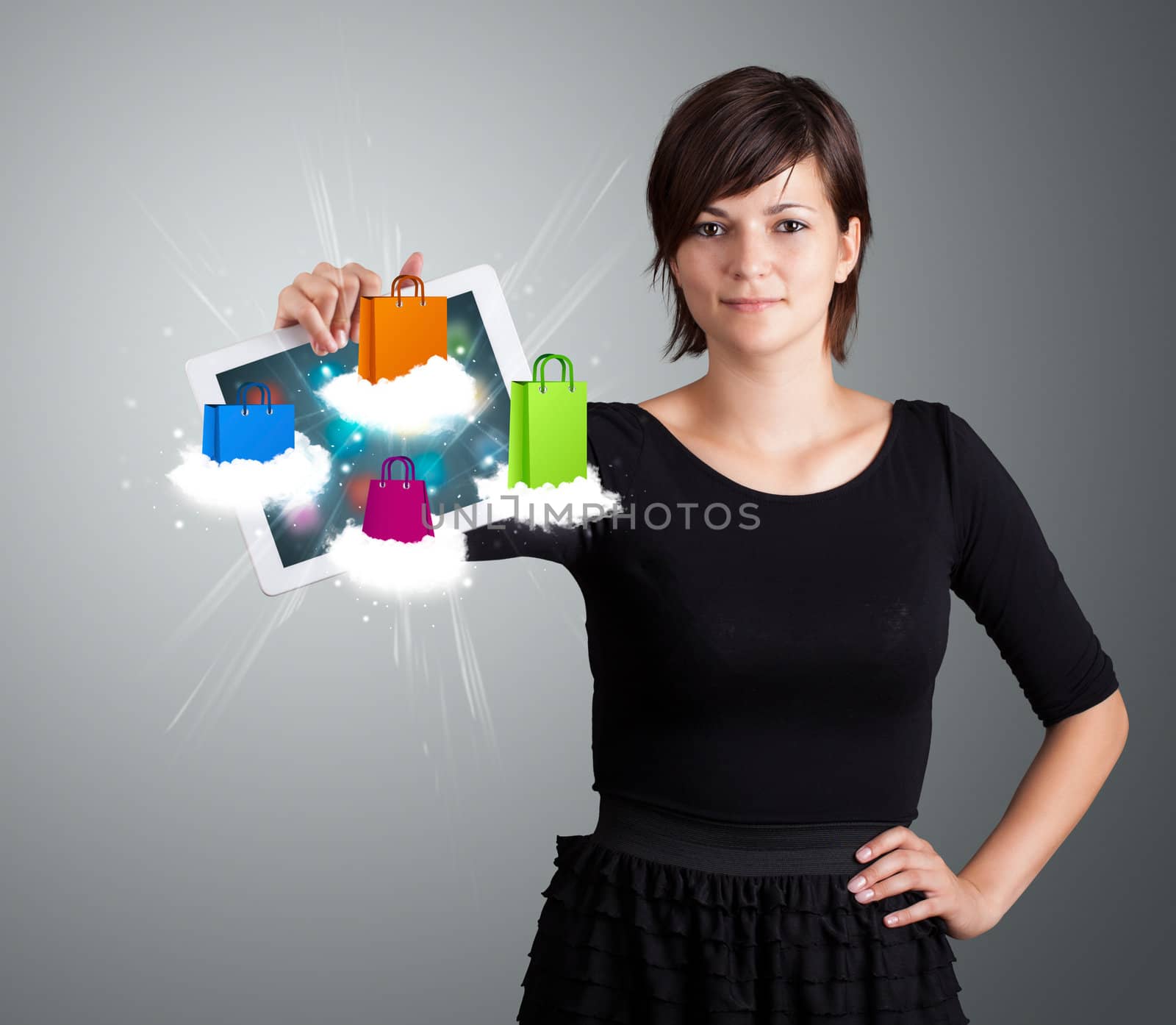 beautiful woman holding modern tablet with colorful shopping bags on clouds