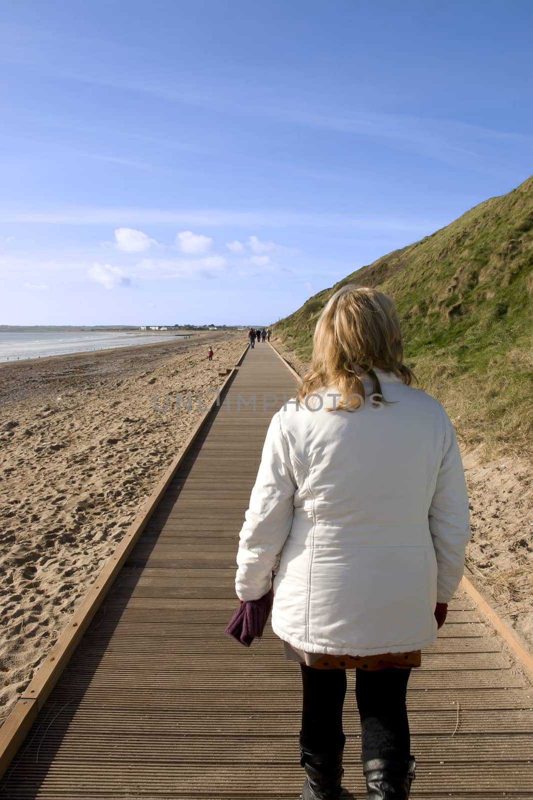 woman walking on beach boardwalk by morrbyte