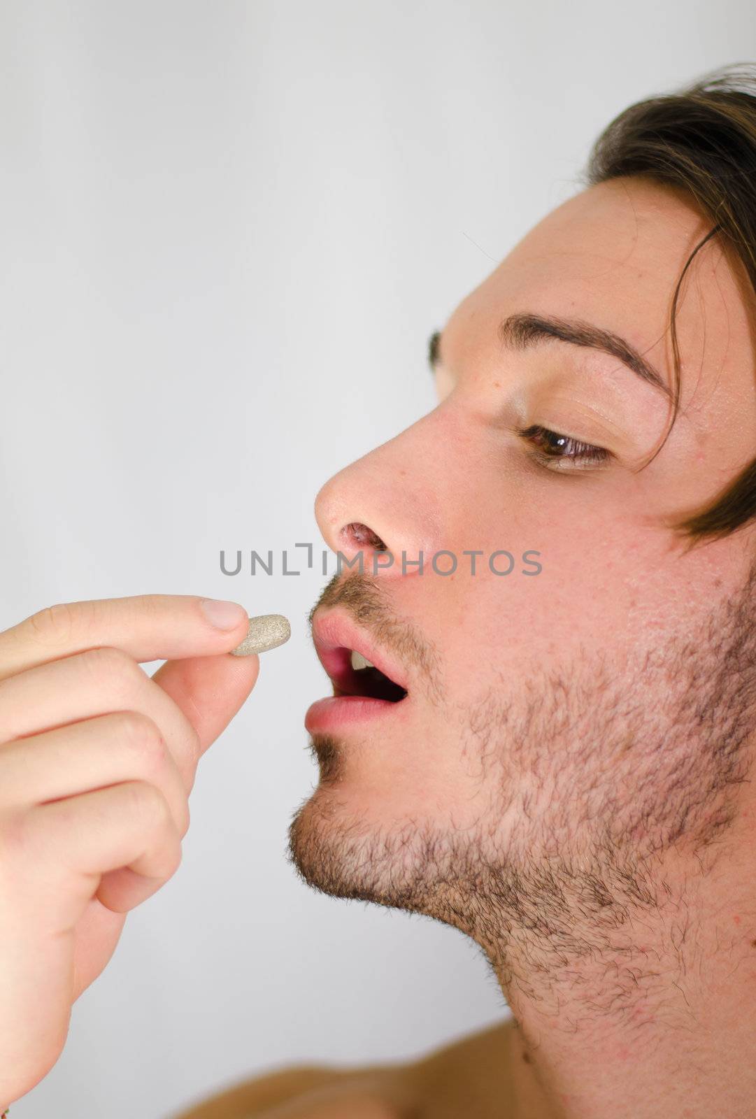 Handsome young man taking pill or medicine capsule by artofphoto