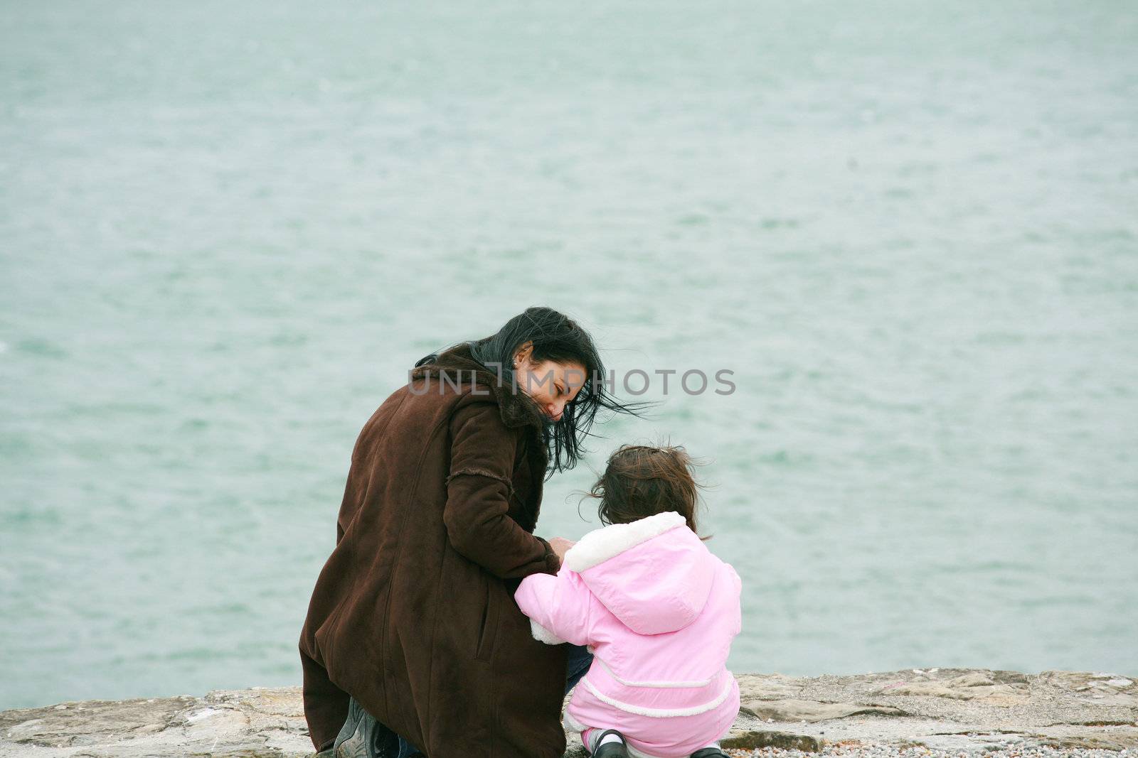 Back view of mother and daughter in beautiful spring sea
