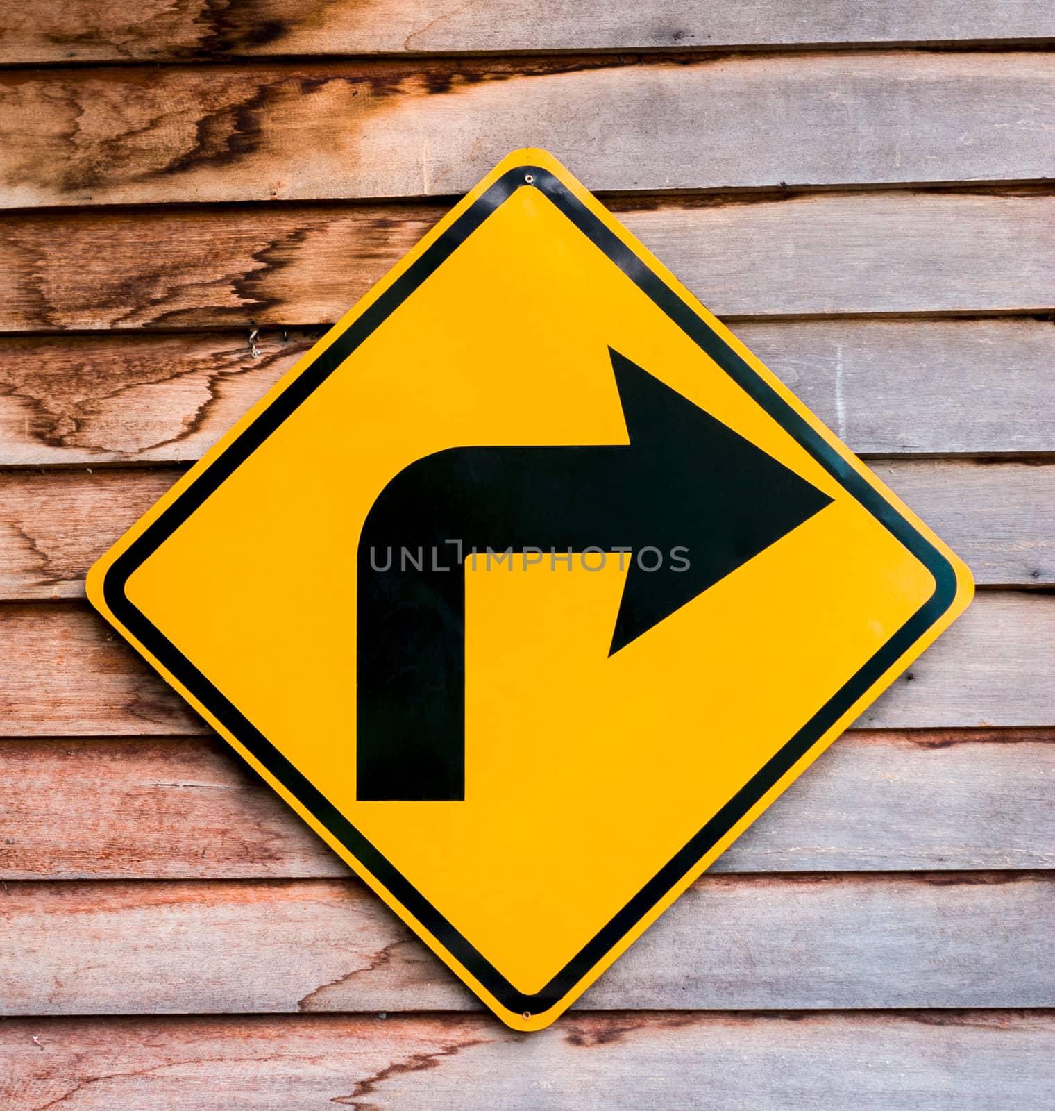 Yellow right turning traffic road sign on a wooden plank