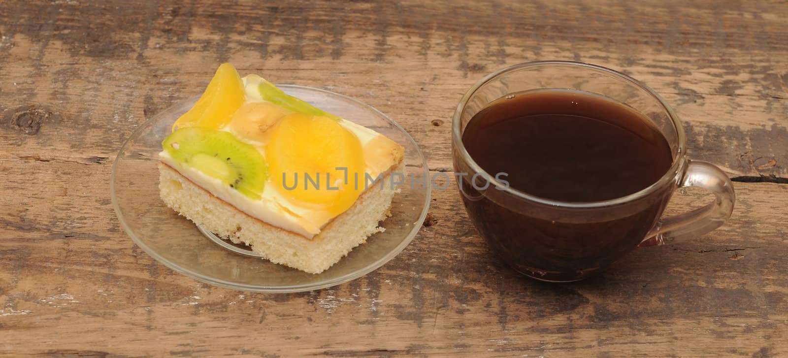 Close-up of glass cup of coffee and apricot cake on wooden table