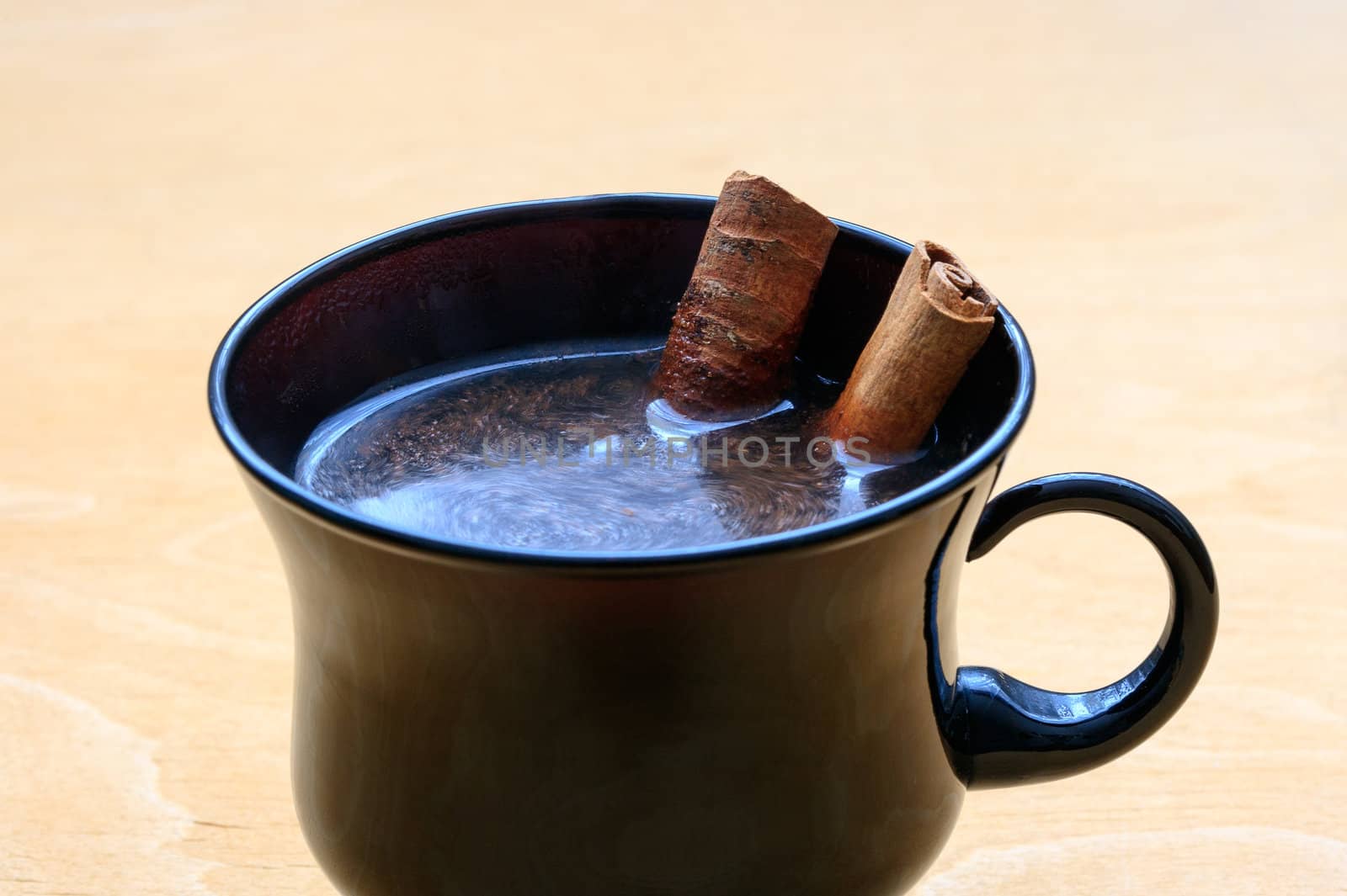 Cup of coffee with cinnamon sticks on wooden table by sfinks