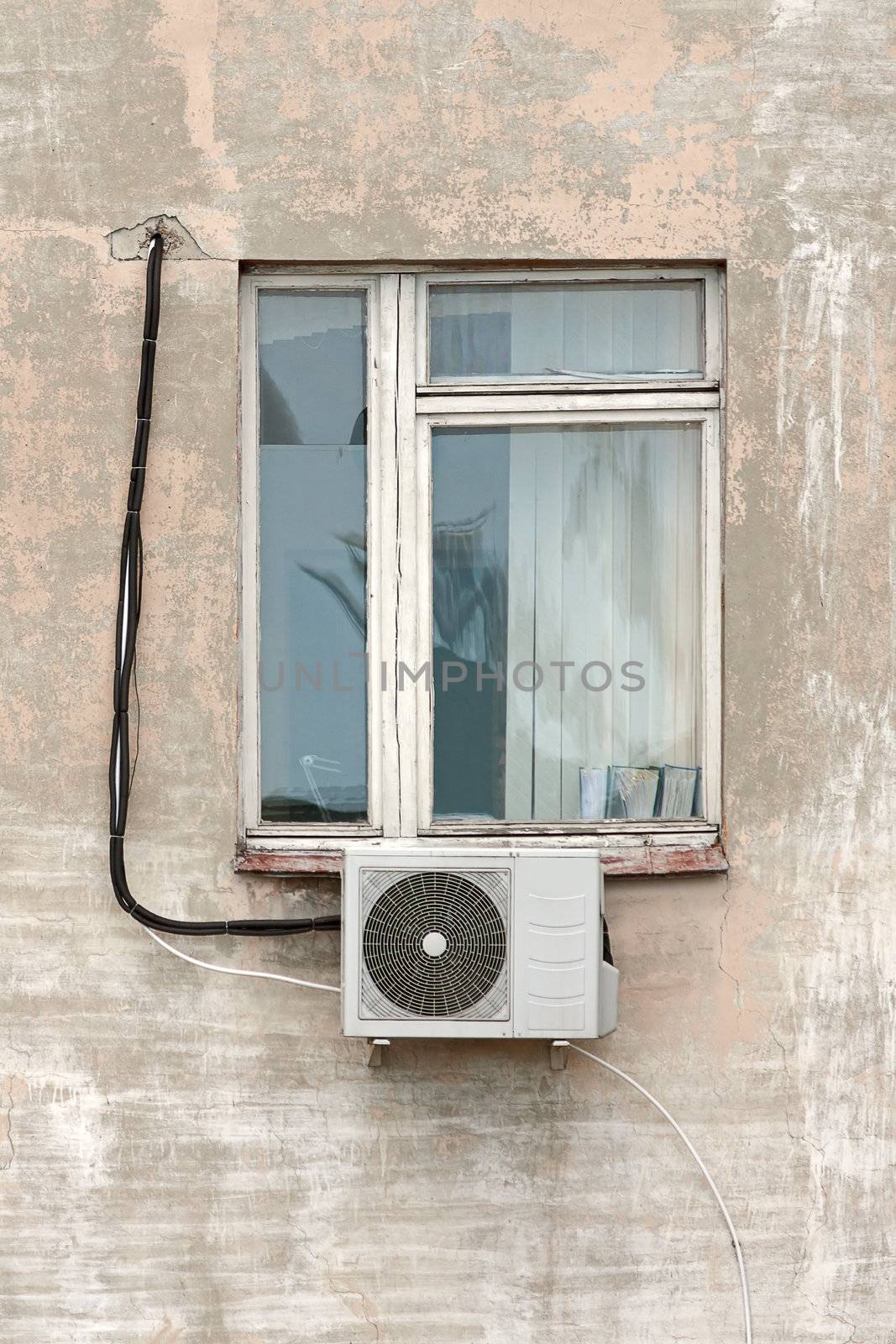 Window with  air conditioning on  background of  old wall of  house.