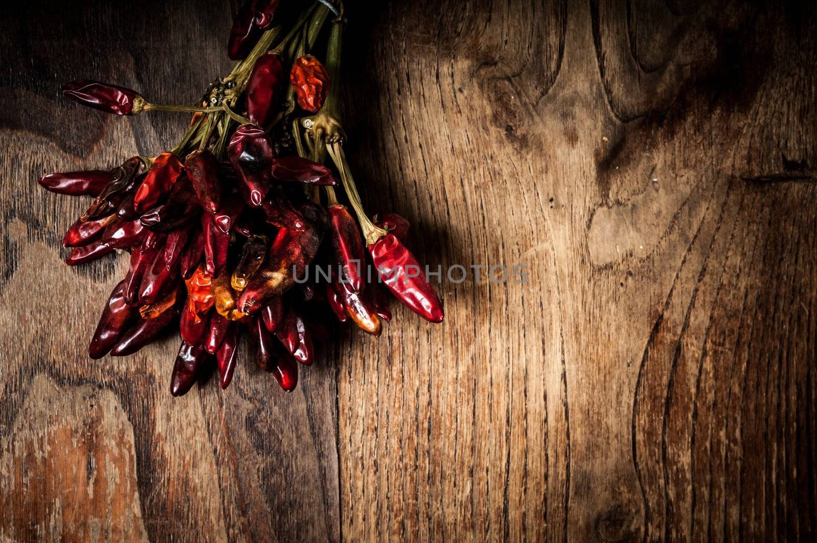 dried hot red chilies on brown textured wood