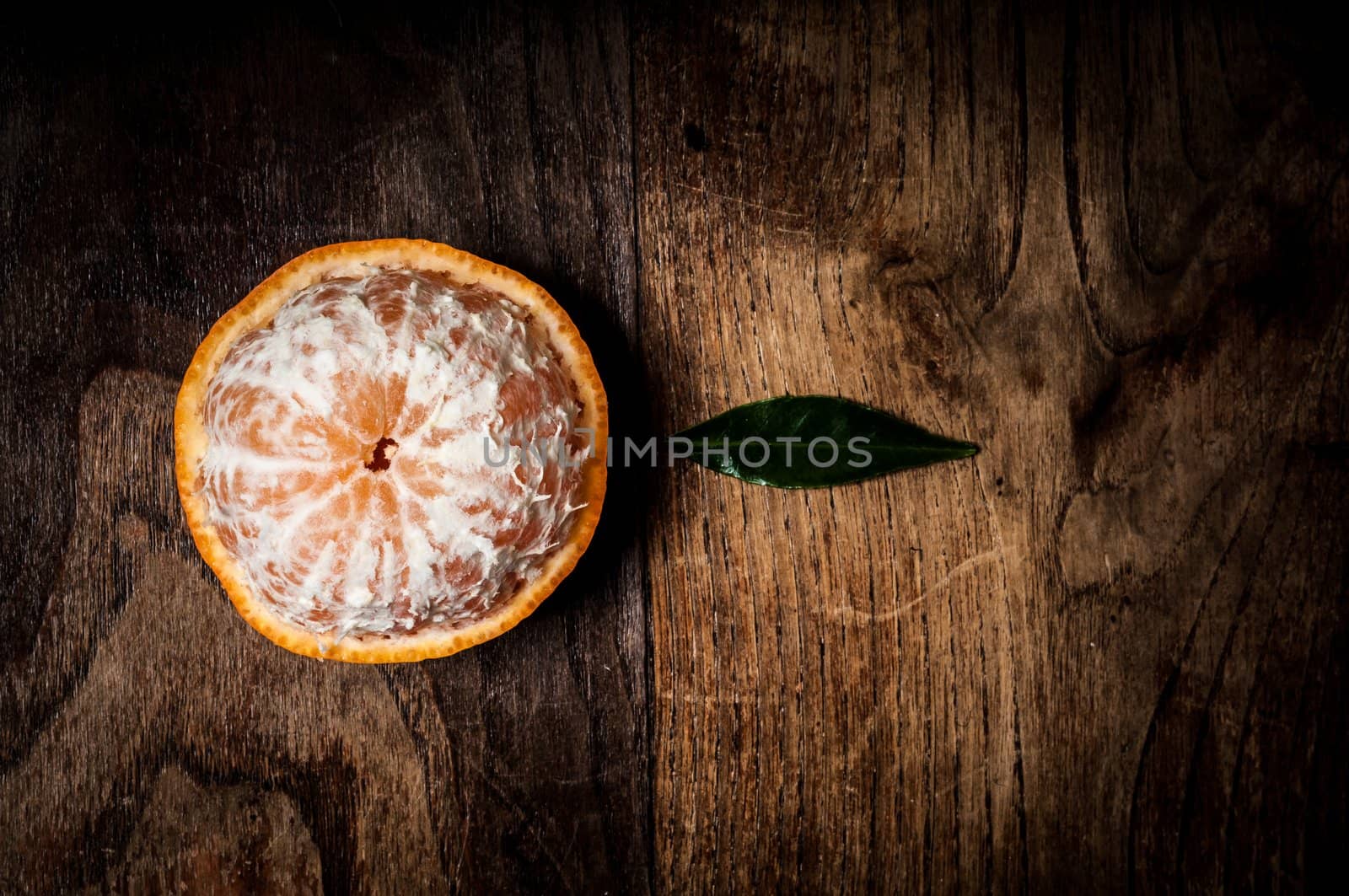 peeled mandarin with leaf on wood by peus