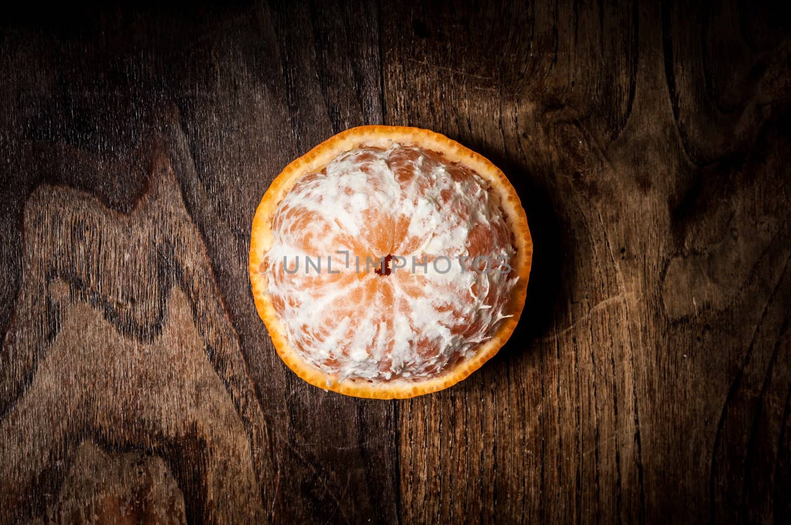peeled mandarin with leaf on brown wood
