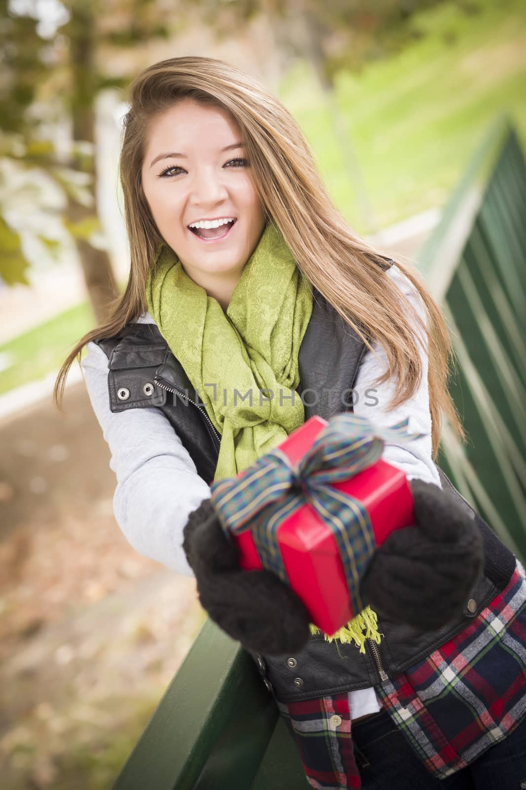 Pretty Festive Smiling Woman with Wrapped Gift with Bow Outside.