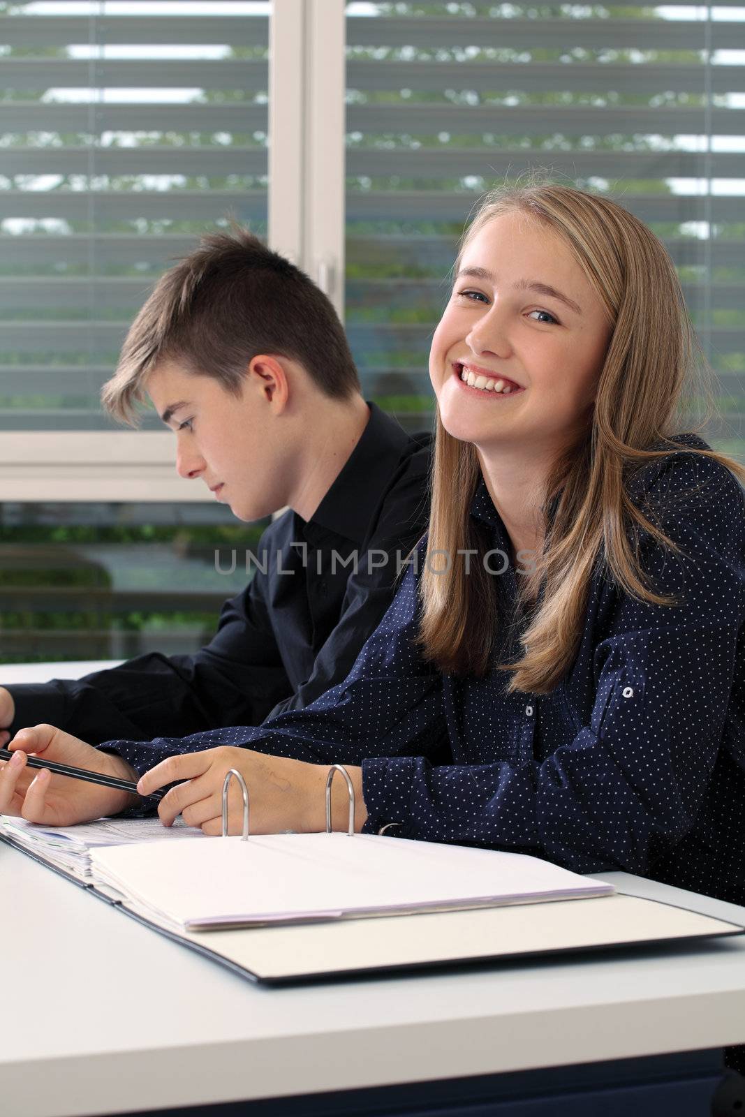 Photo of two students in their class writing in their notebooks.