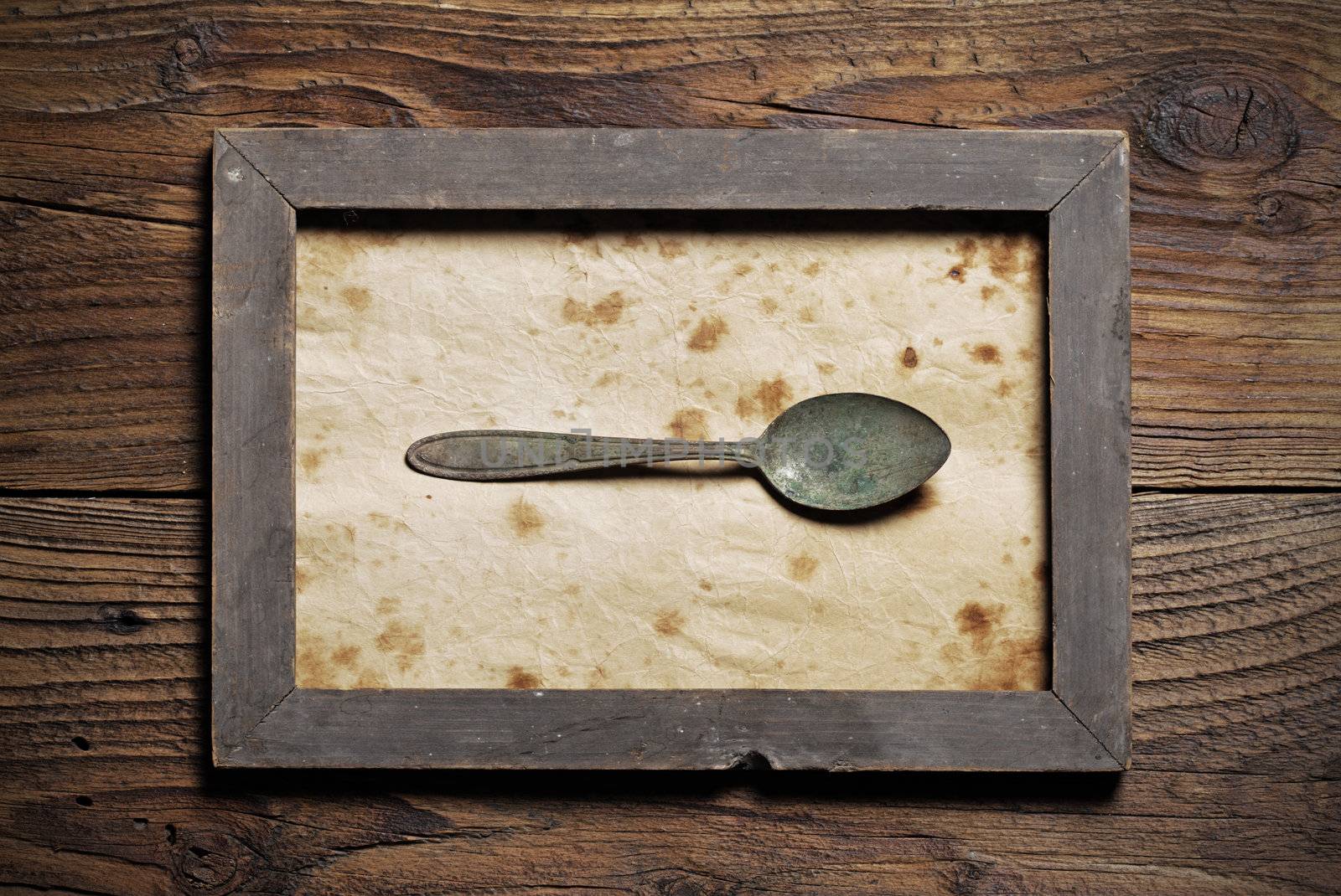 Metal spoon framed on old wood background by stokkete