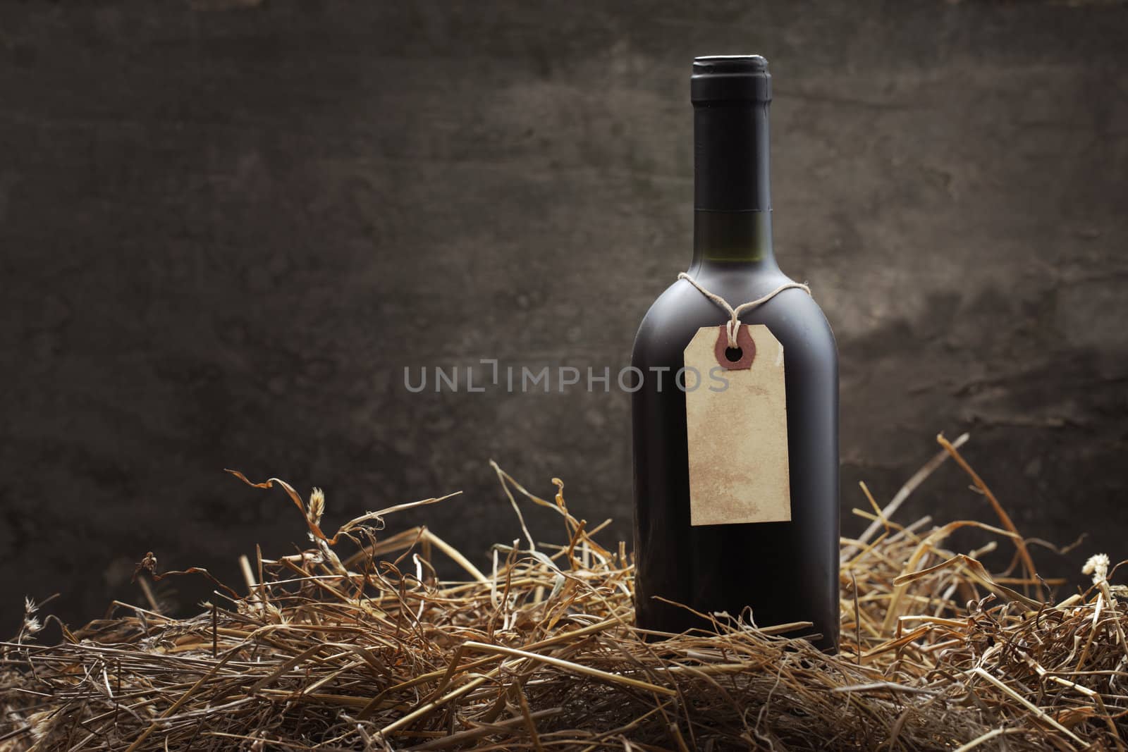 Bottle of red wine in the straw, copy space on vintage label