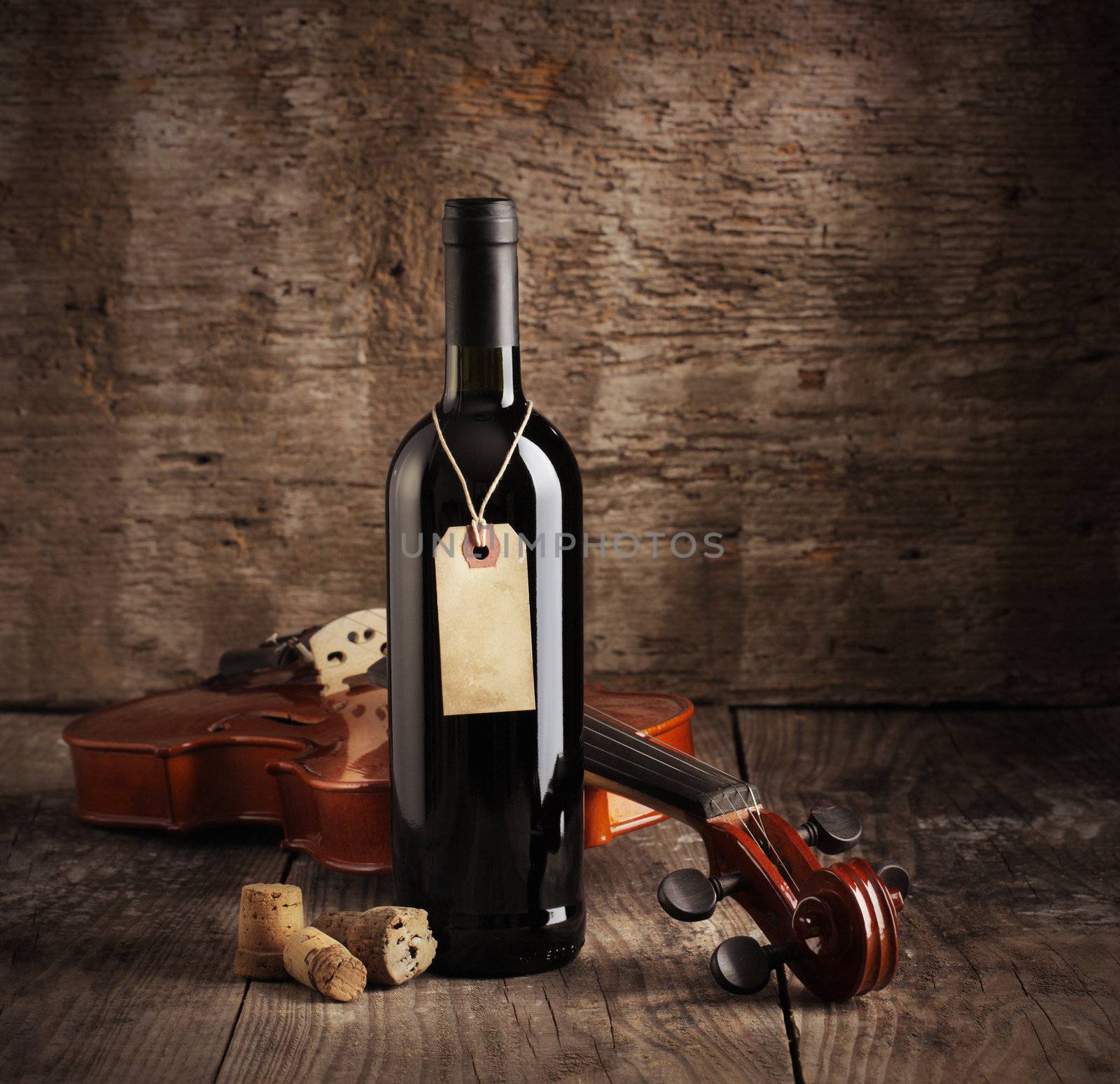 Red wine bottle and violin on wooden background