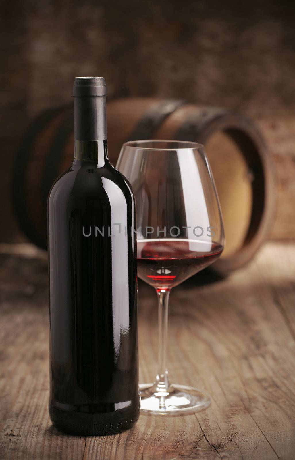 Wine bottle with glass,  barrel on background