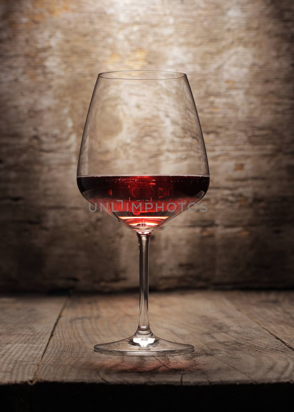 Red wine glass on wooden background by stokkete