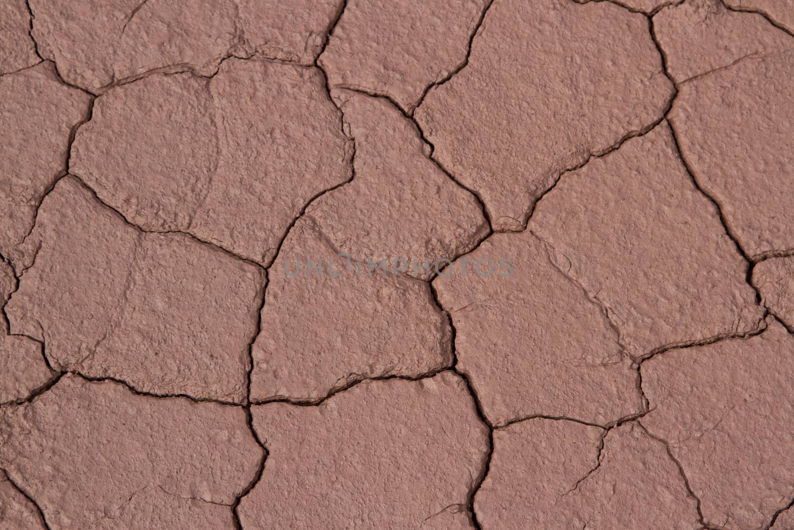 A dried patch of red clay earth with cracks making a mosaic pattern