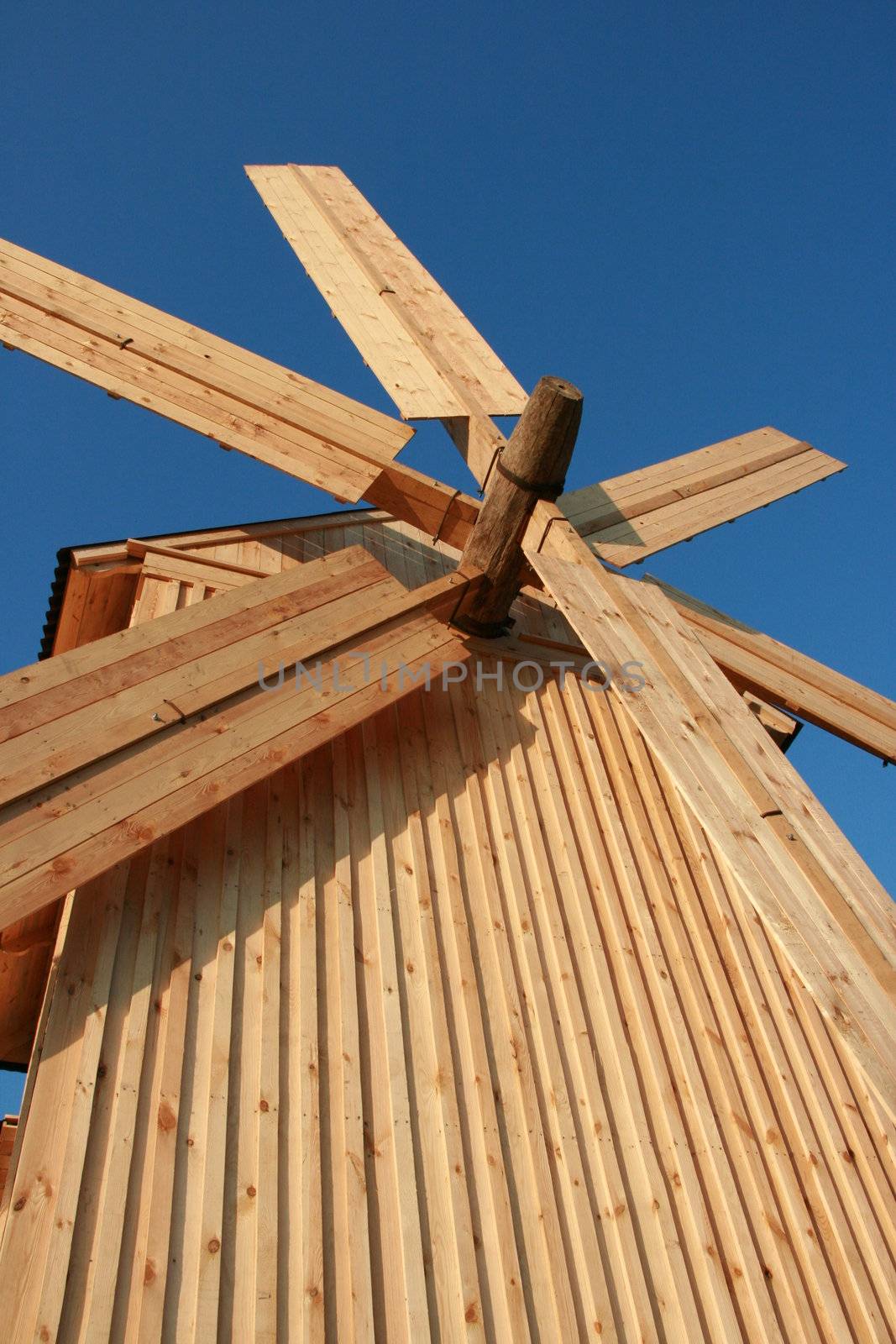 wooden windmill against blue sky by fotosergio