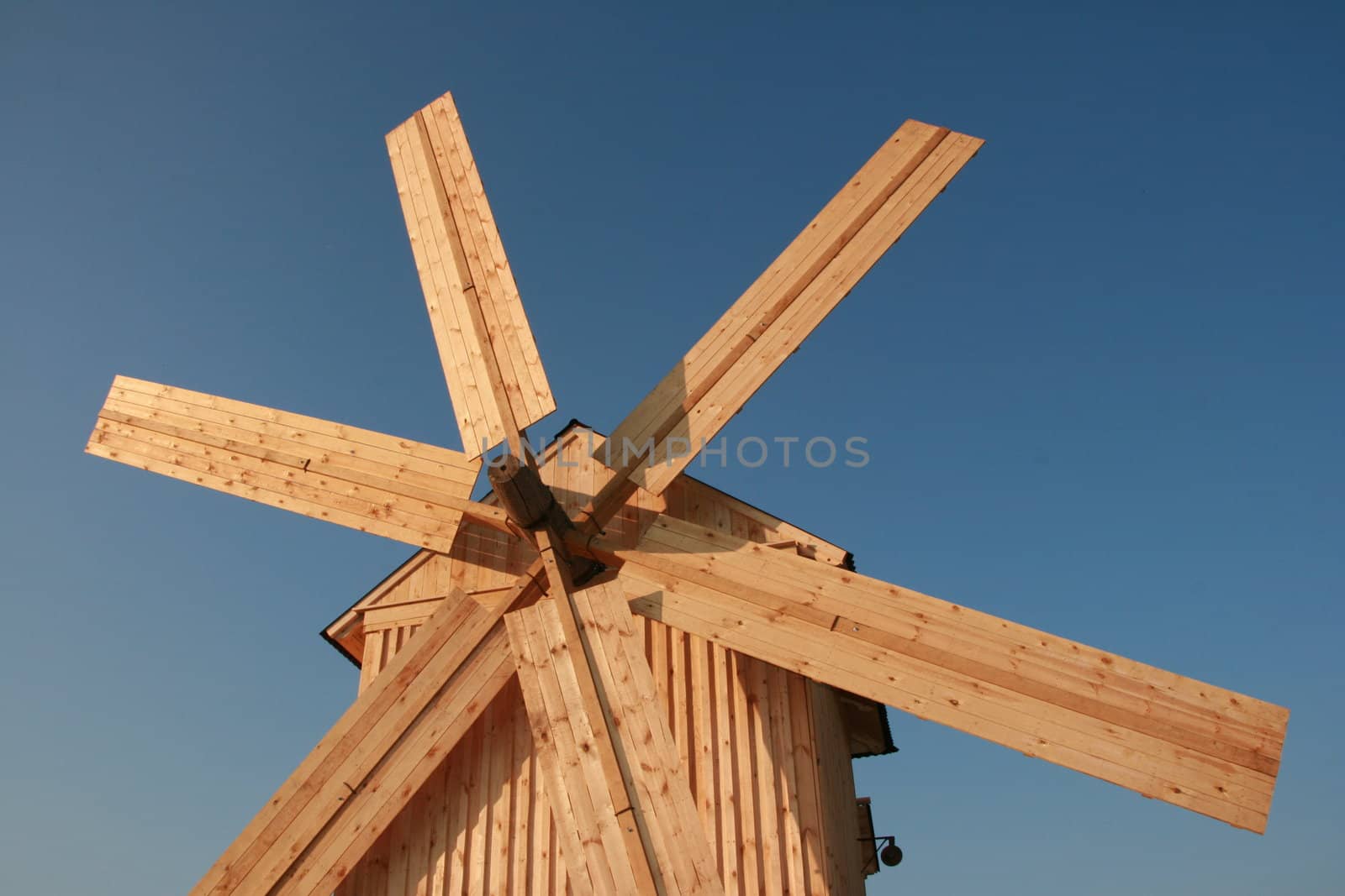 wooden windmill against blue sky by fotosergio