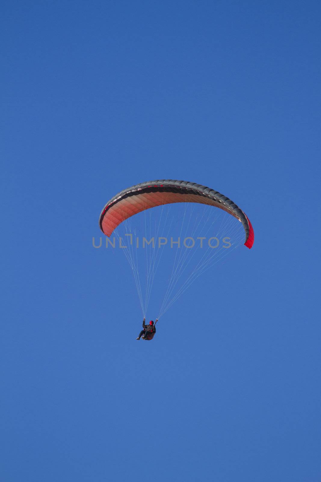 A paraglider takes to the sky. Shot from below against a blue sky.