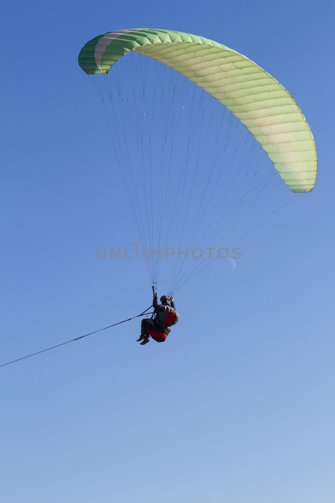 A paraglider takes to the sky. Shot from below against a blue sky.