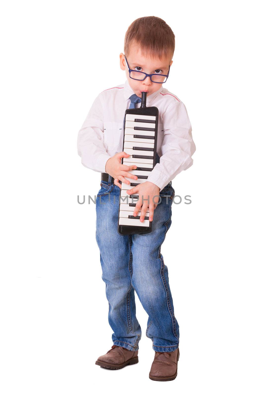 Preschool boy in glasses, jeans and white shirt playing melodica, isolated on white background