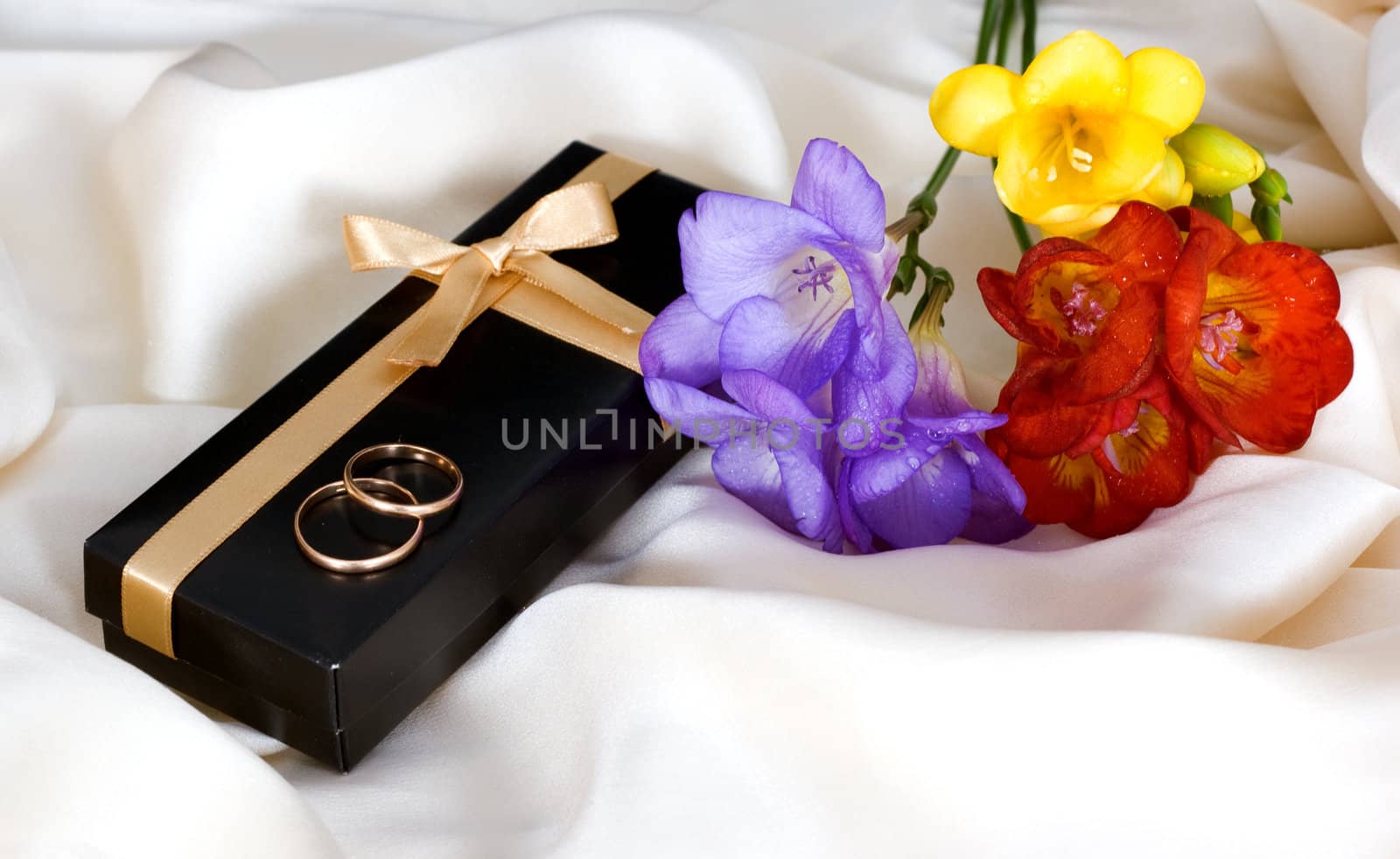 Bouquet of multicolored freesia, a gift from the wedding rings on delicate silk