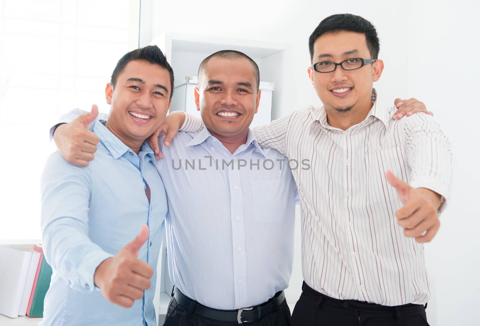 Thumbs up Southeast Asian businessmen standing in office